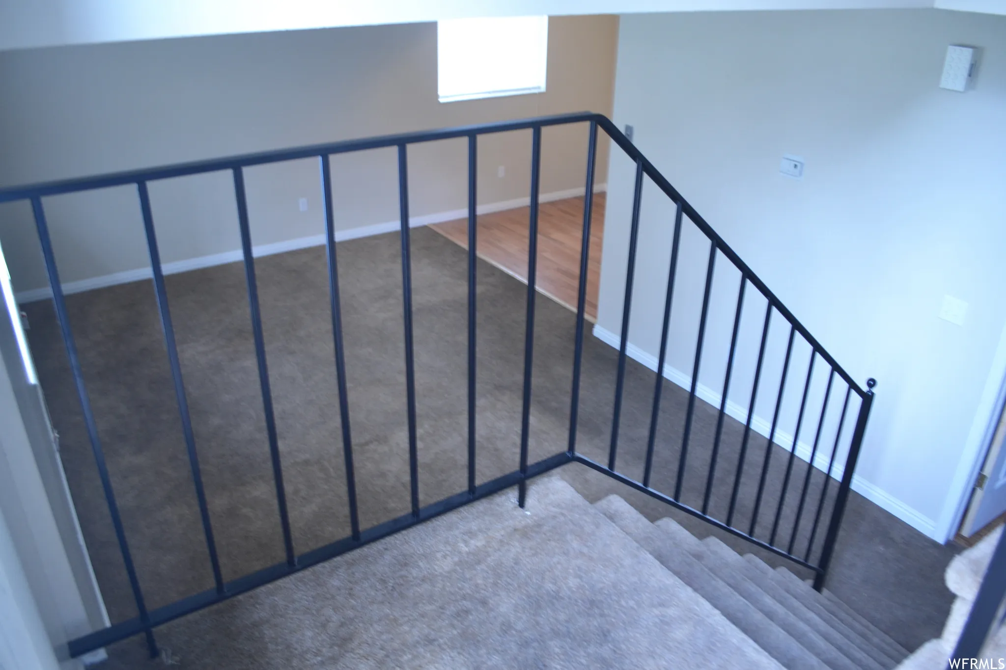 Carpeted staircase with black metal railings
