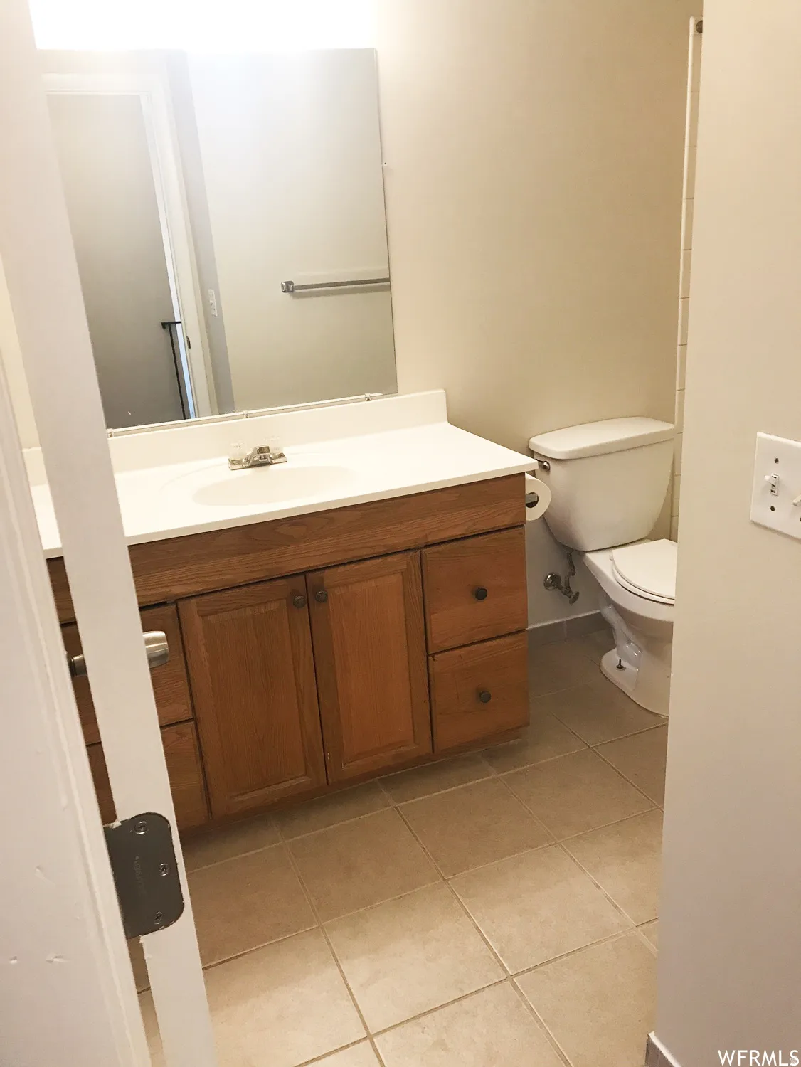 Bathroom featuring a wood vanity with a white countertop, an integrated sink, and a large wall-mounted mirror