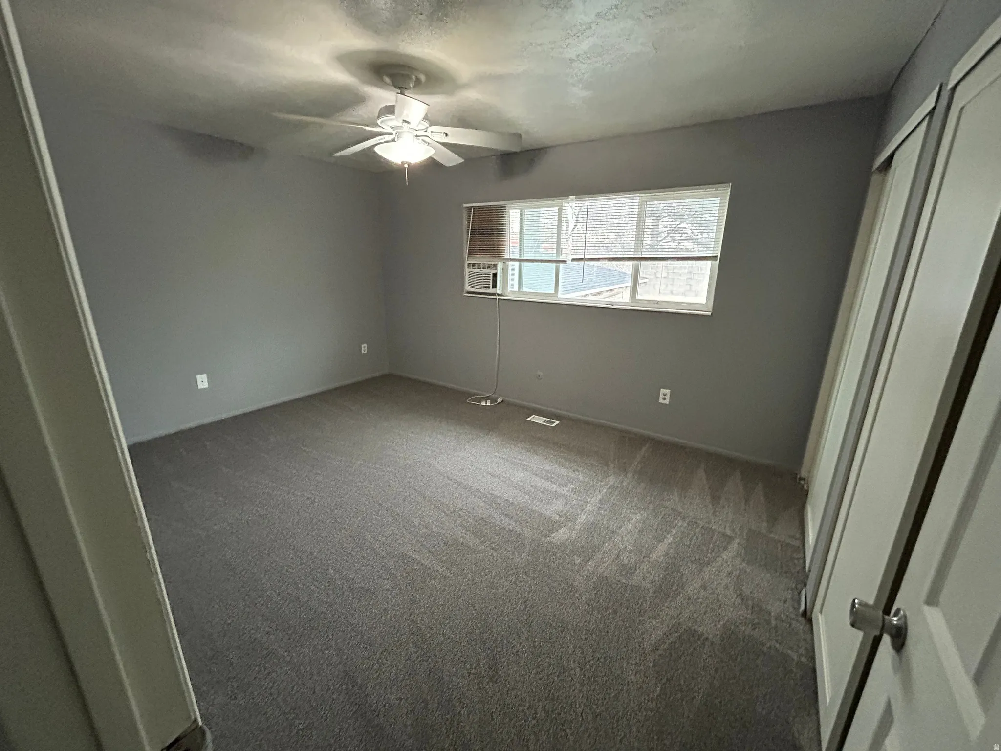 Bedroom featuring neutral gray walls, gray carpet flooring, a ceiling fan with integrated lighting, a window with horizontal blinds, and a built-in closet with sliding doors