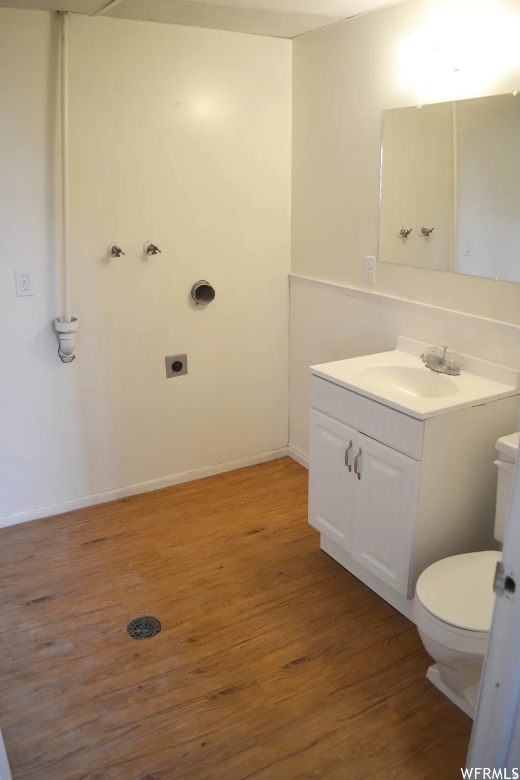 Utility room featuring wood-finish flooring, white walls, and a dedicated plumbing hookup for a washing machine