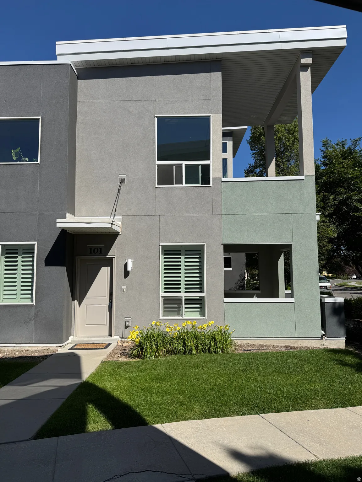 Contemporary multi-level exterior featuring a stucco facade in varying shades of gray and green