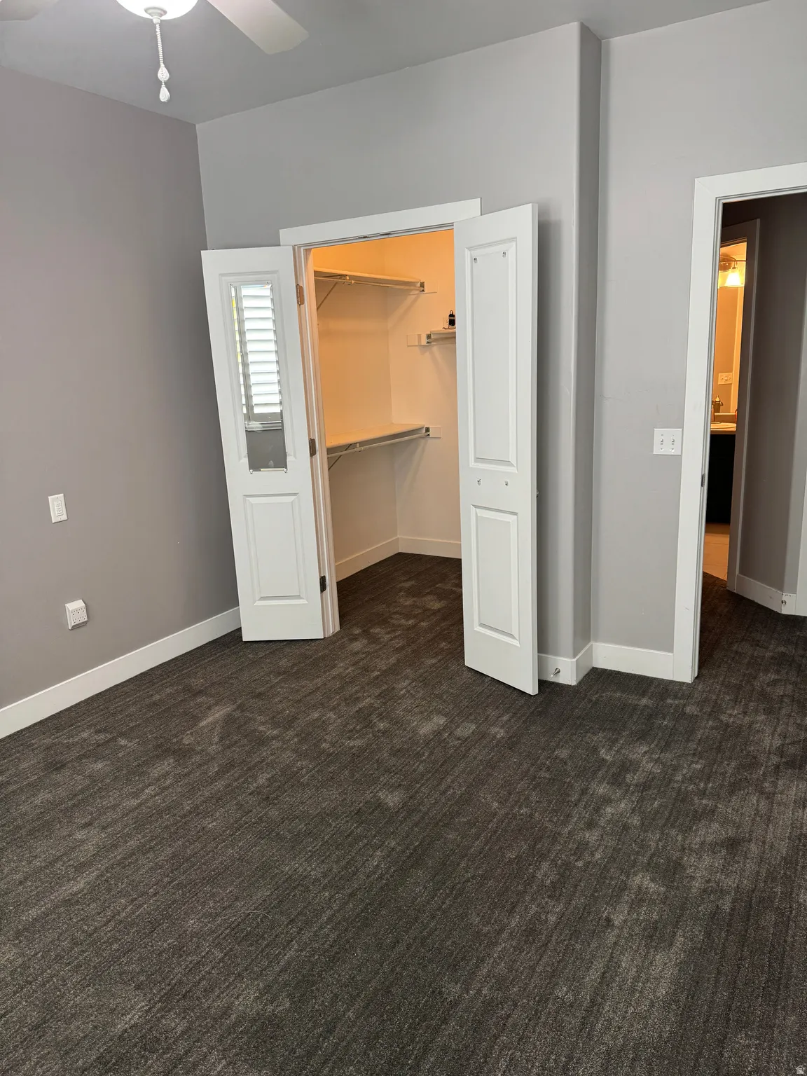 Spacious room featuring patterned carpet flooring, light gray wall paint, and white trim