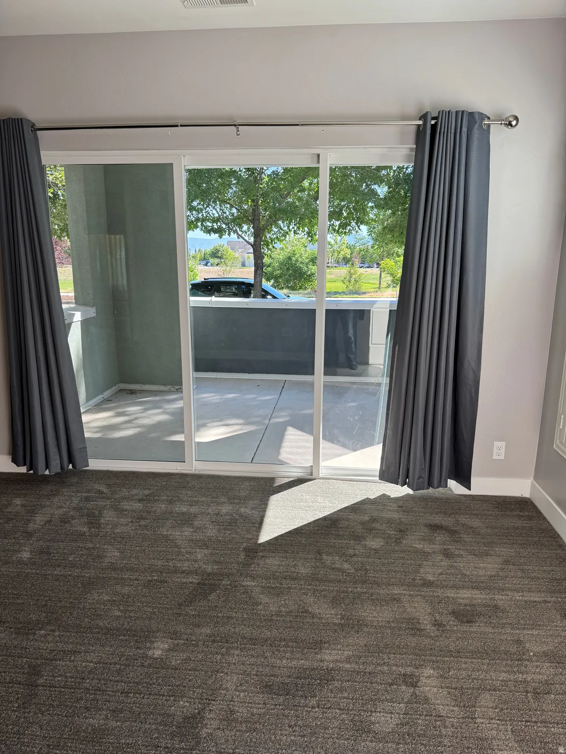 Sliding glass door leading to an outdoor patio with a partial stone wall and built-in counter