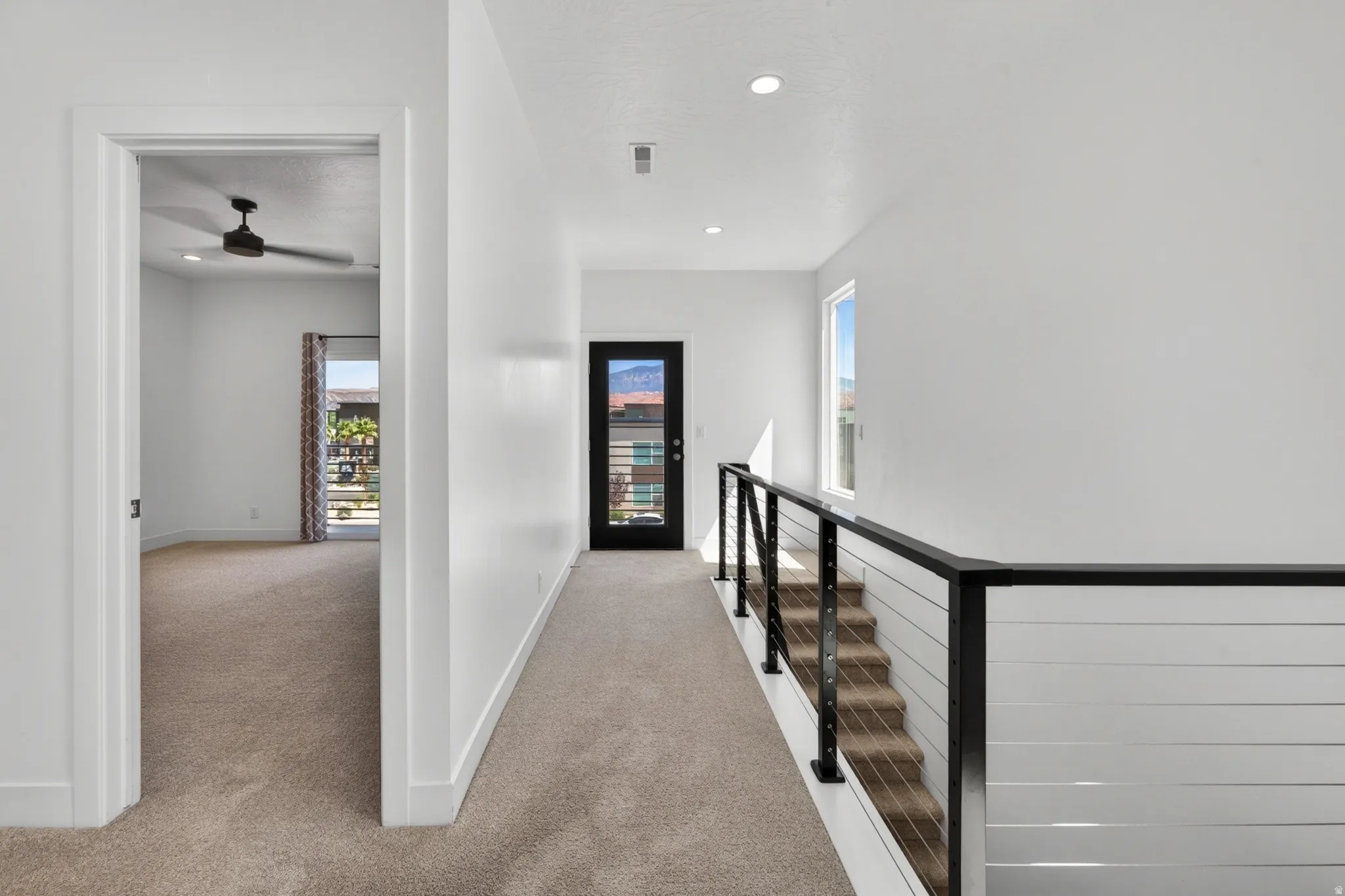 Upper-level hallway featuring a modern cable railing system and recessed lighting