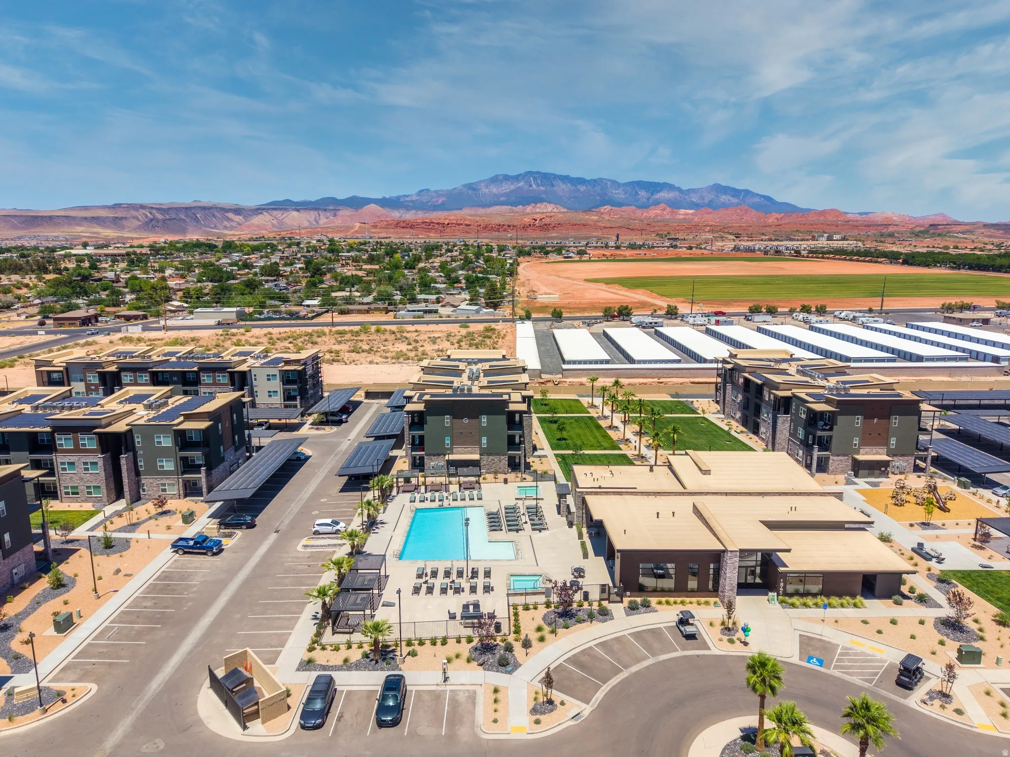 Modern apartment complex featuring multiple buildings with solar panel carports and rooftop solar arrays