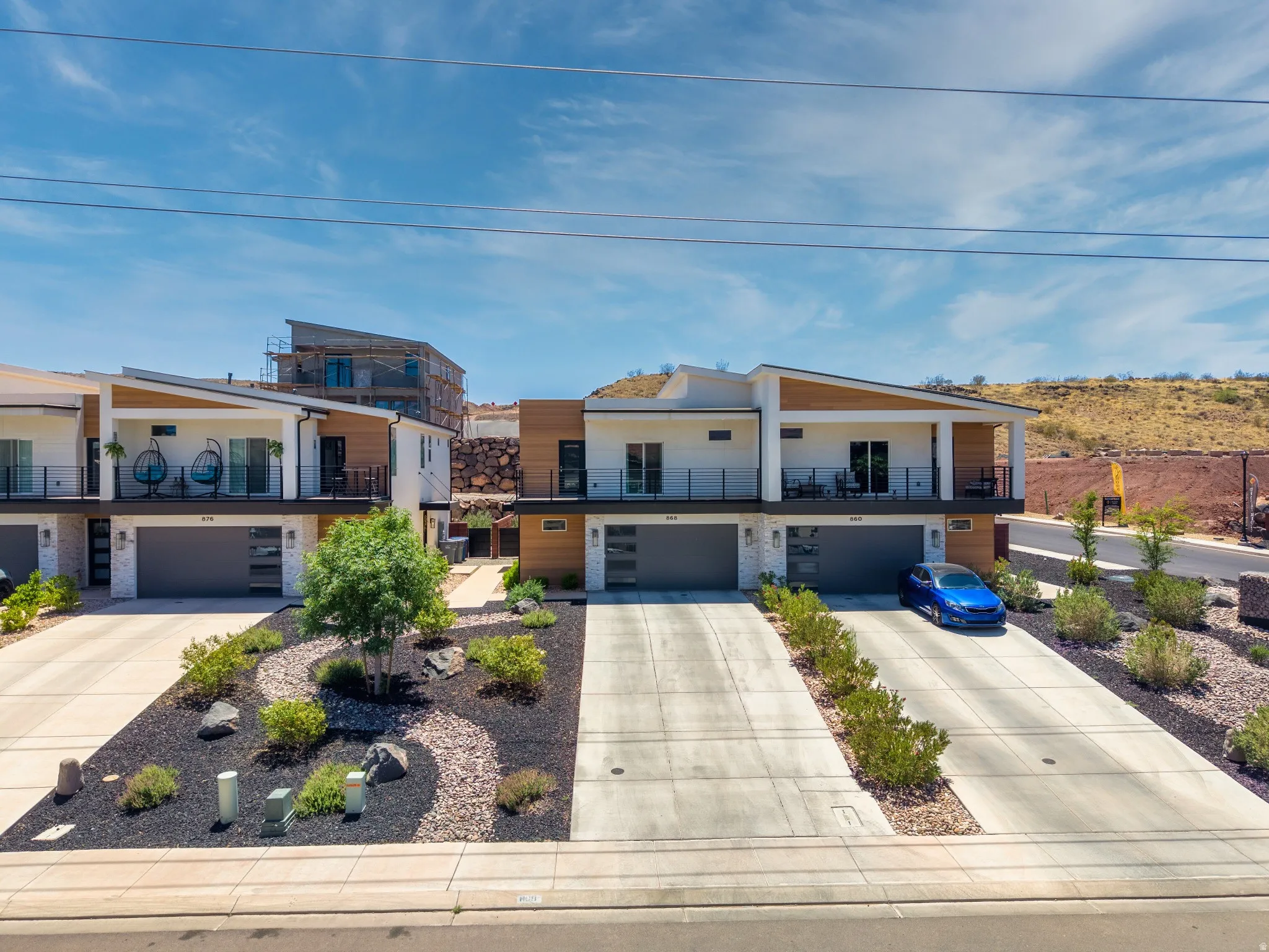 Contemporary townhome exteriors featuring white stucco, wood-finish siding accents, and stone details
