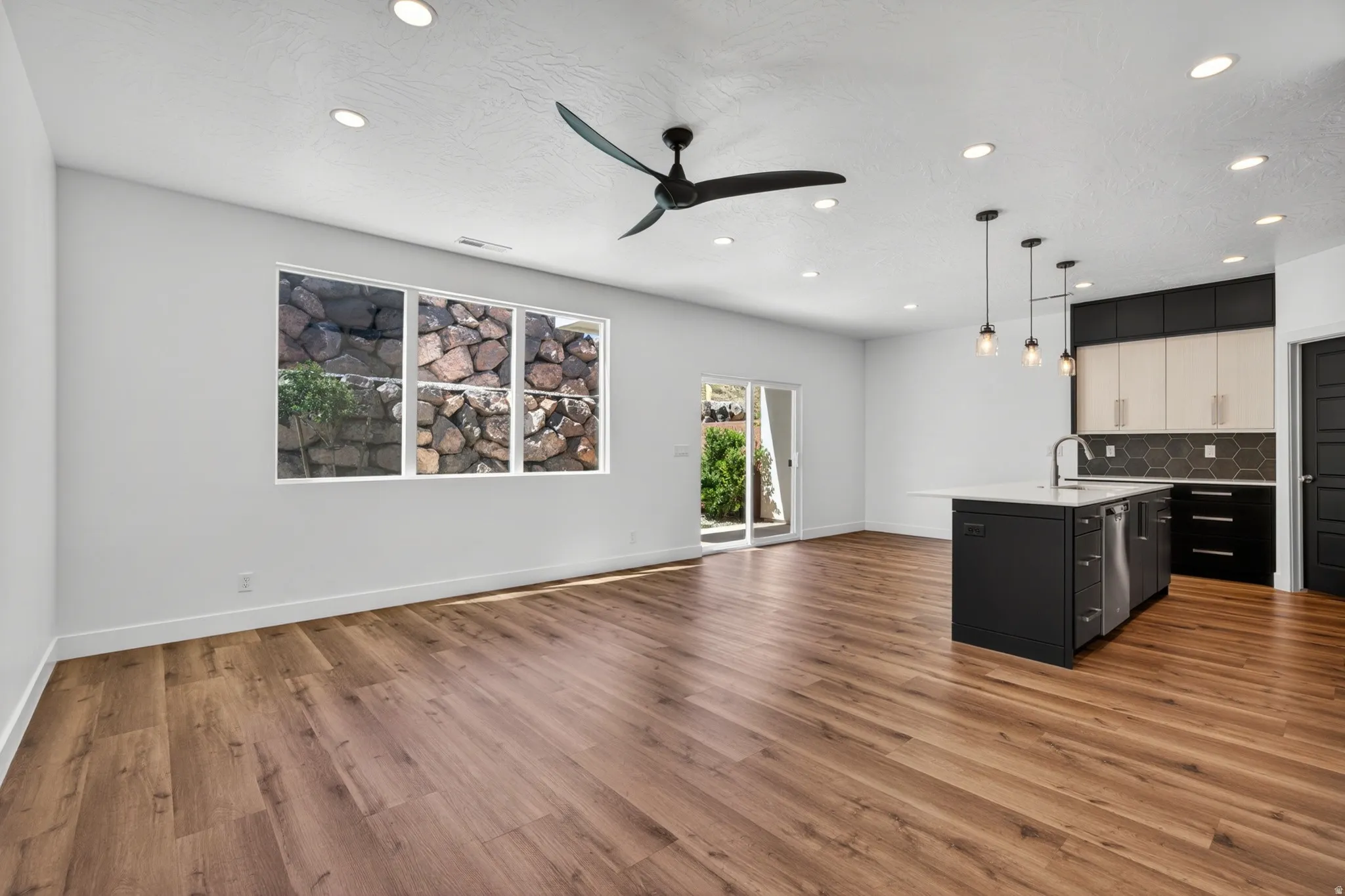 Open-concept living area featuring wood-finish flooring, recessed lighting, and a modern ceiling fan