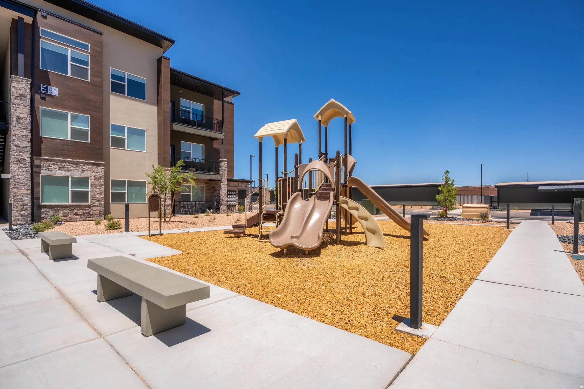 Outdoor play area featuring multiple slides, climbing elements, and a wood chip surface