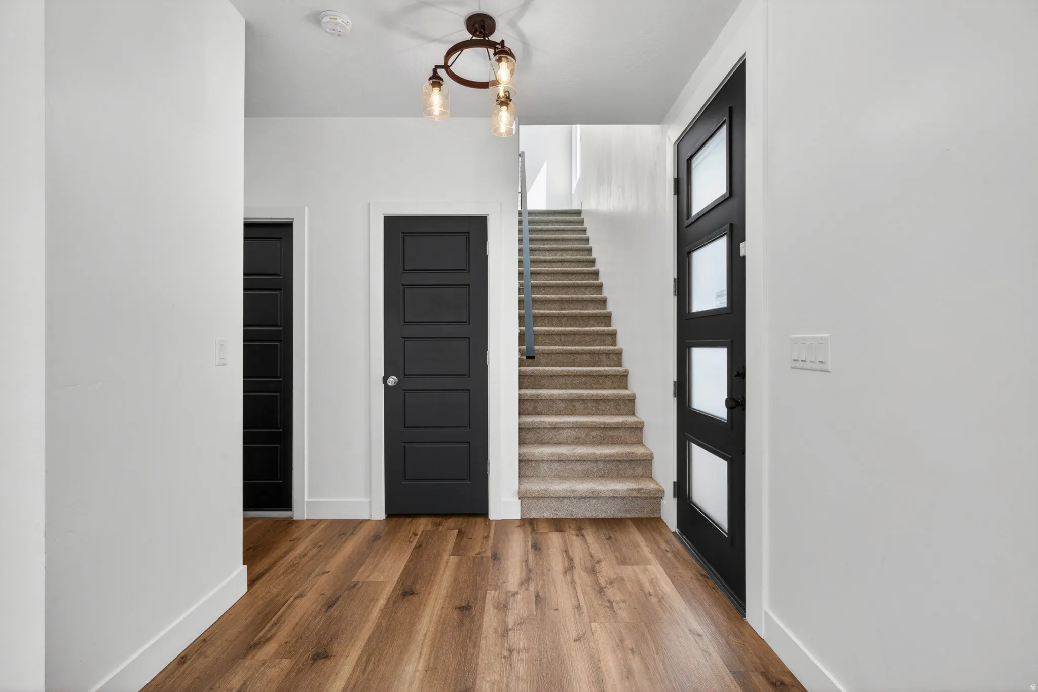 Entryway featuring wood-finish flooring, white walls, and a modern chandelier