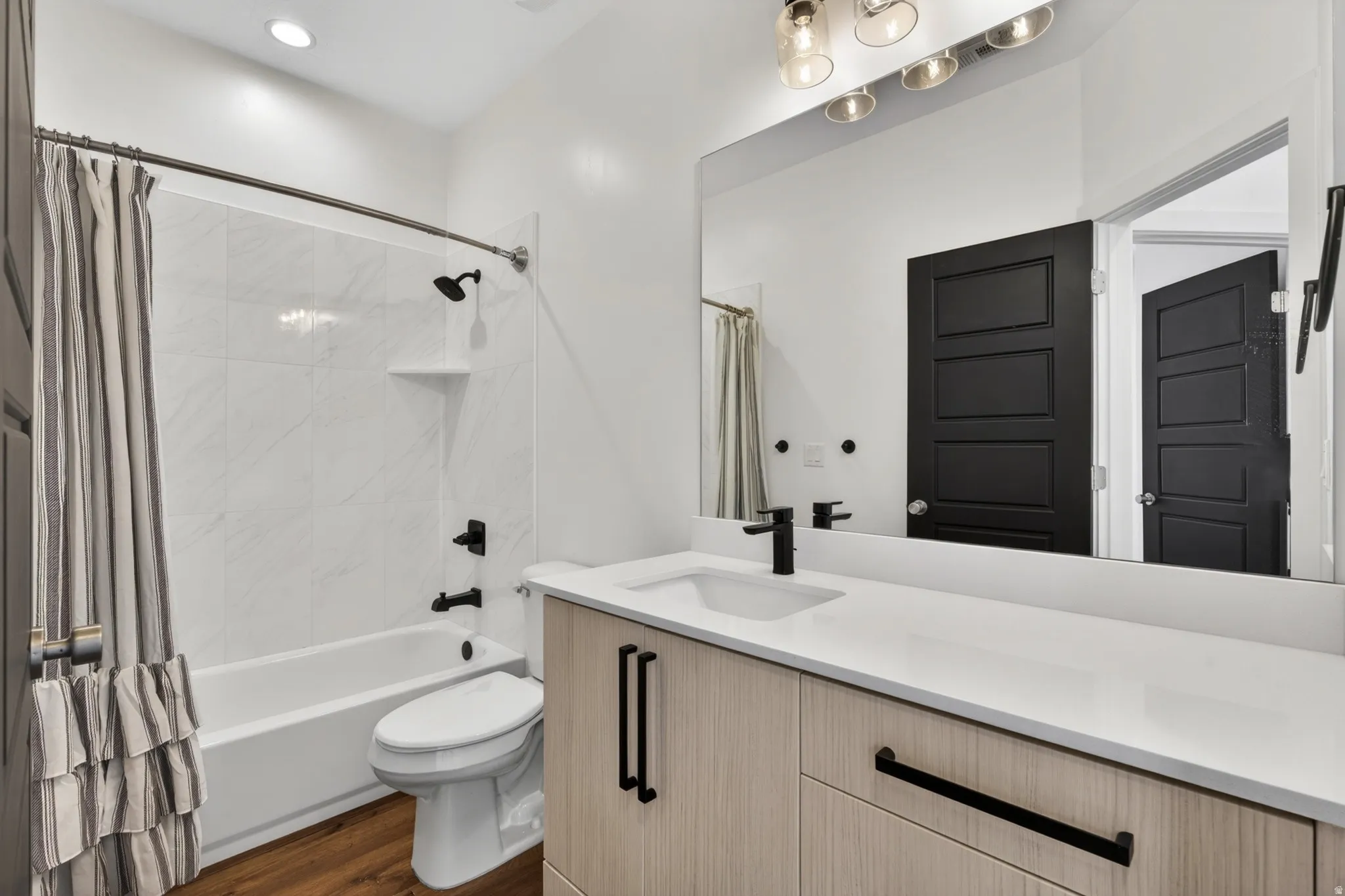Contemporary bathroom featuring wood-finish flooring and a white vanity with a recessed sink