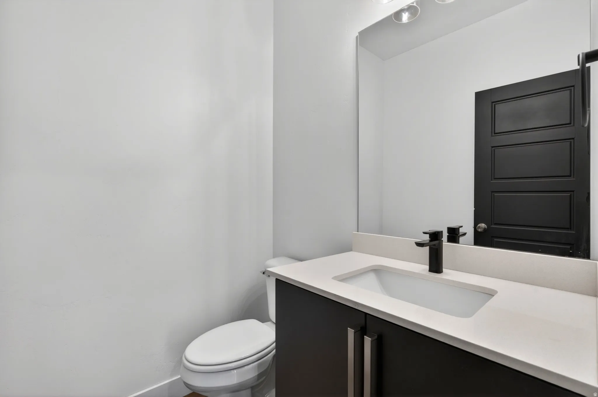 Bathroom vanity featuring a flat-panel cabinet with brushed nickel hardware, a light-toned countertop, and an integrated rectangular sink