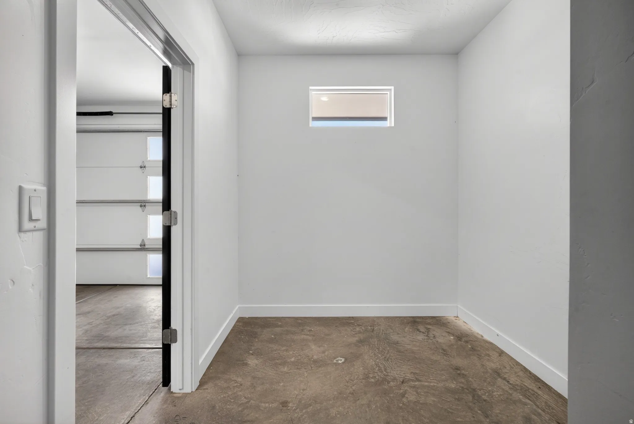 Storage area featuring a small transom window and concrete flooring