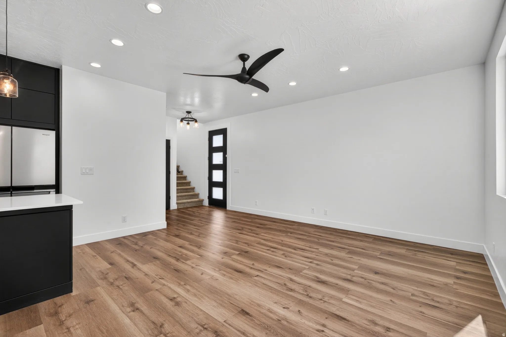 Open-concept living area featuring wood-finish flooring, recessed lighting, and a contemporary black ceiling fan