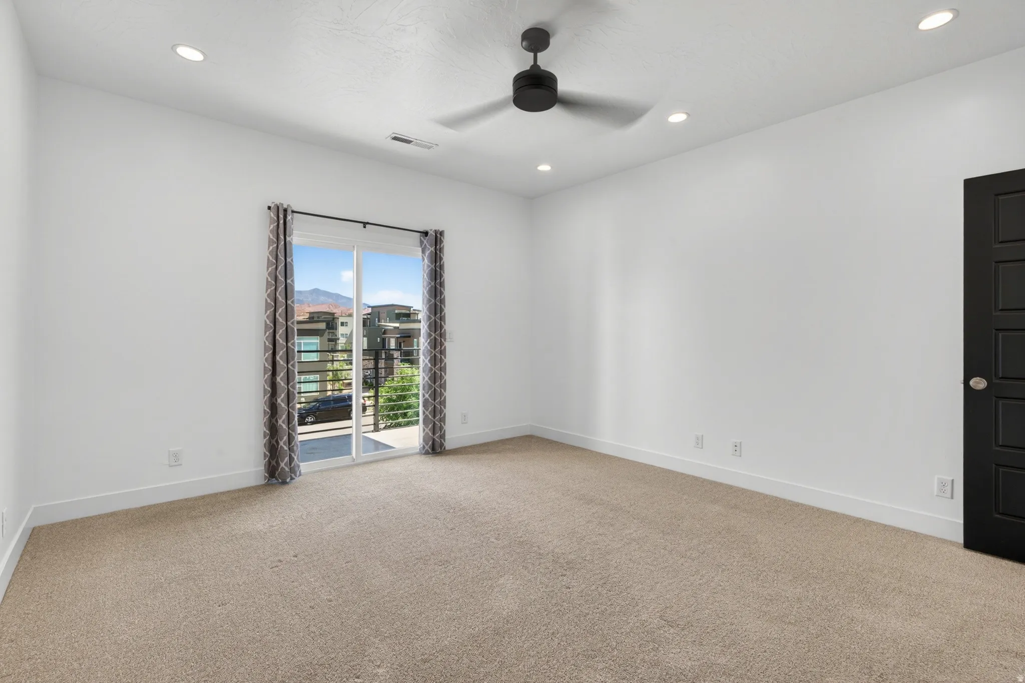 Carpeted room with white walls, a black ceiling fan, and recessed lighting