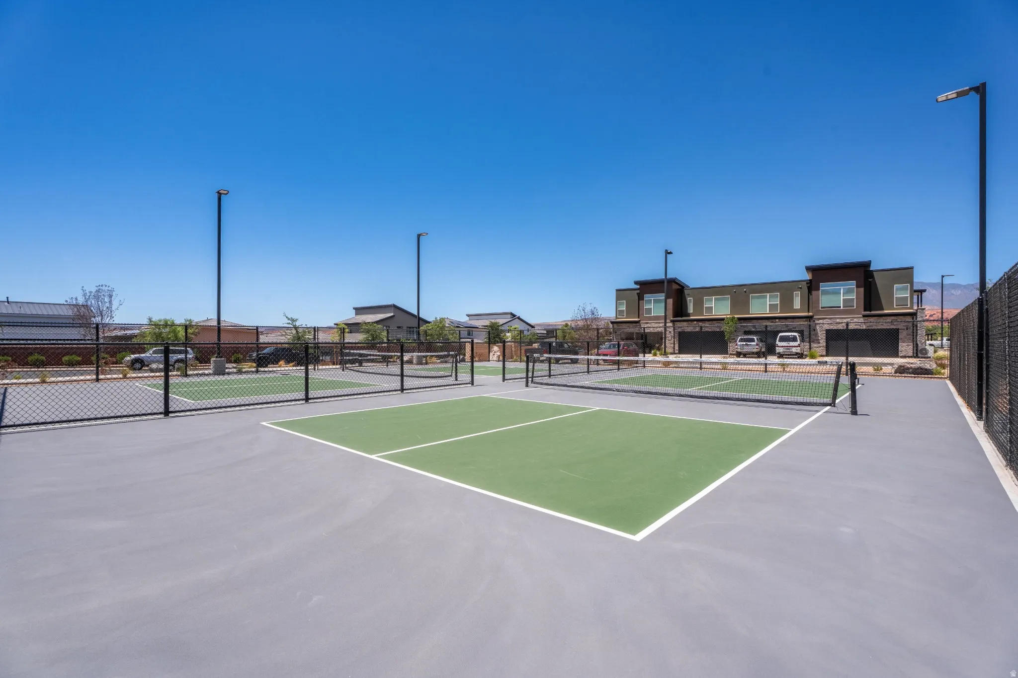 Multiple outdoor pickleball courts with perimeter fencing and integrated lighting