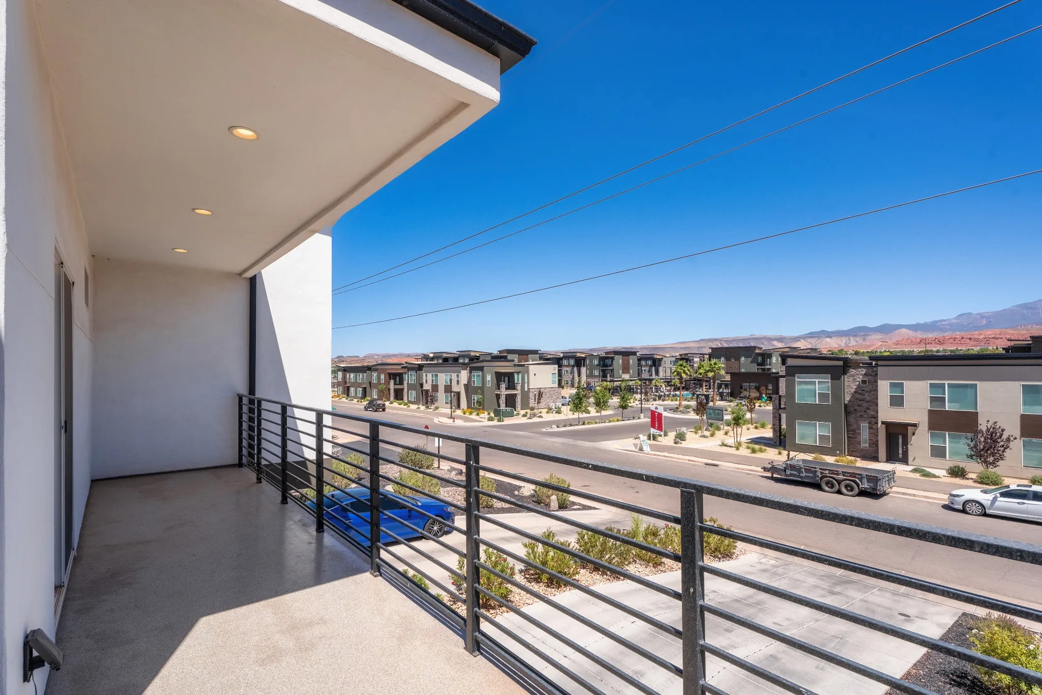 Balcony featuring a concrete surface, black metal railings, and recessed ceiling lighting