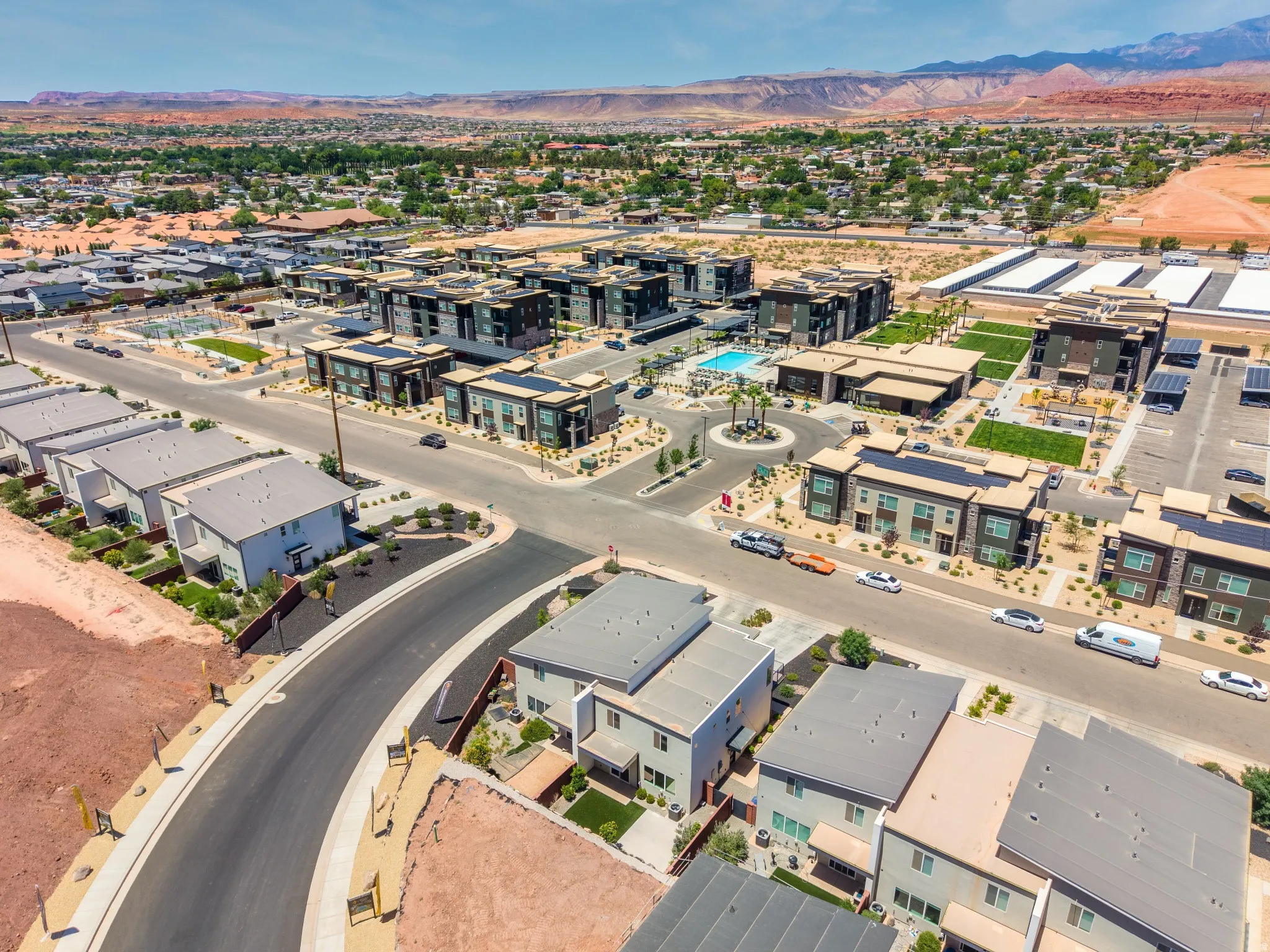 Contemporary multi-unit development featuring a community pool, landscaped grounds, covered parking, and mountain scenery