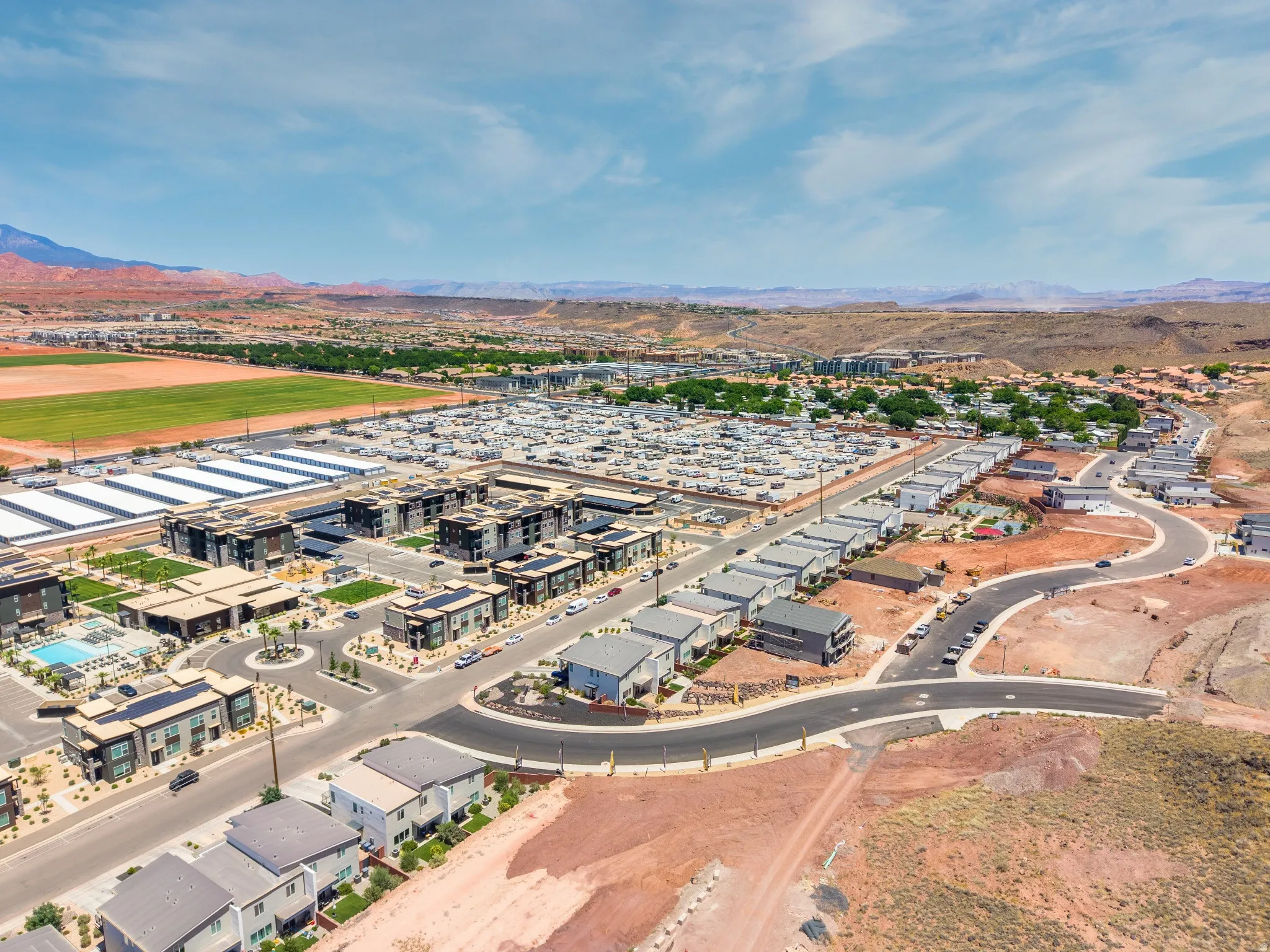 Aerial perspective showcasing a developing community with residential buildings, roadways, and mountainous terrain in the background