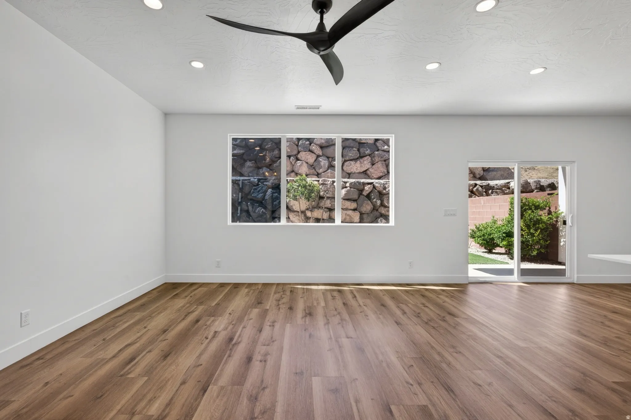 Spacious room featuring wood-finish flooring, recessed lighting, and a modern ceiling fan
