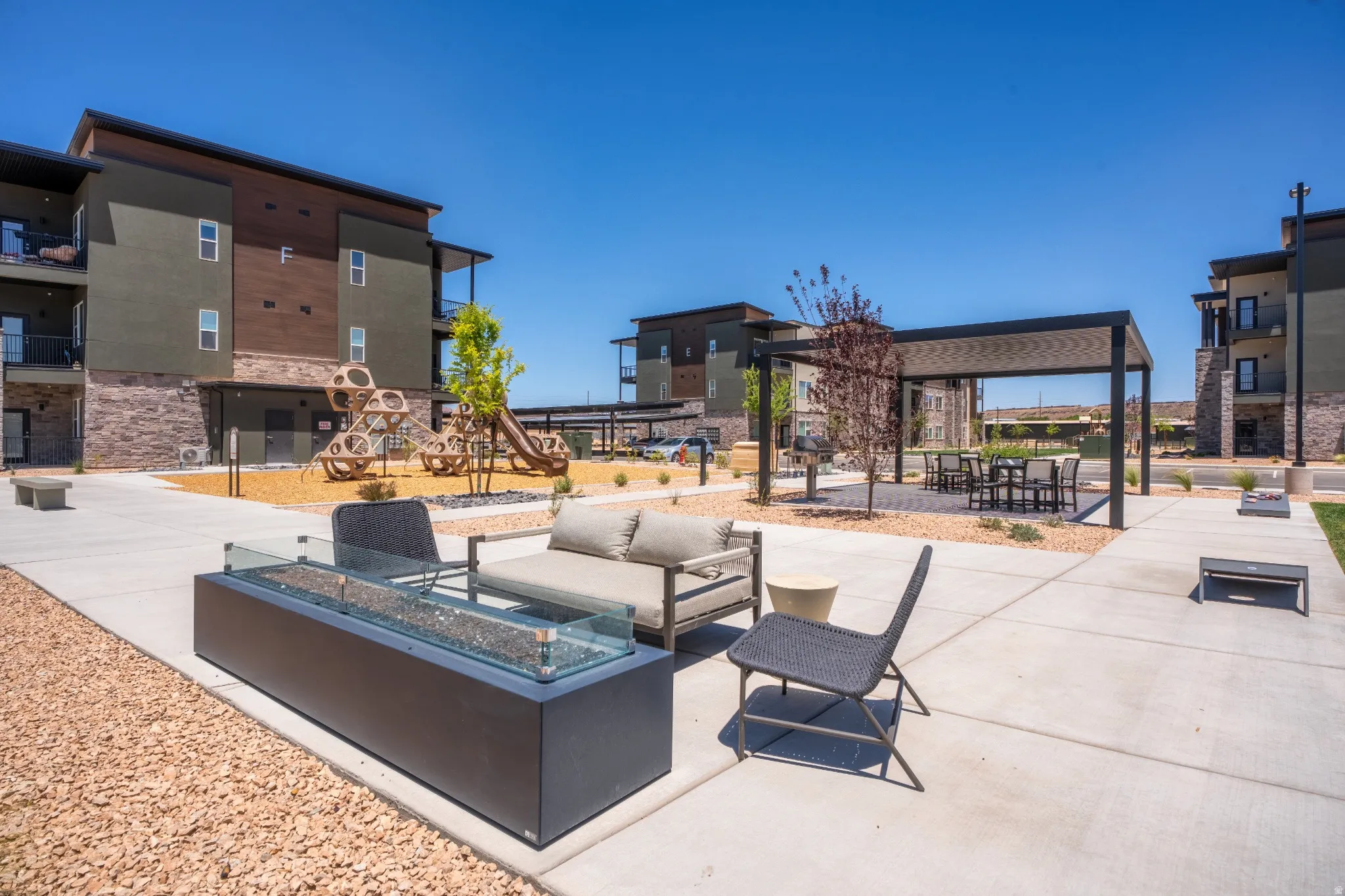 Outdoor lounge area featuring a modern rectangular fire pit with a glass barrier