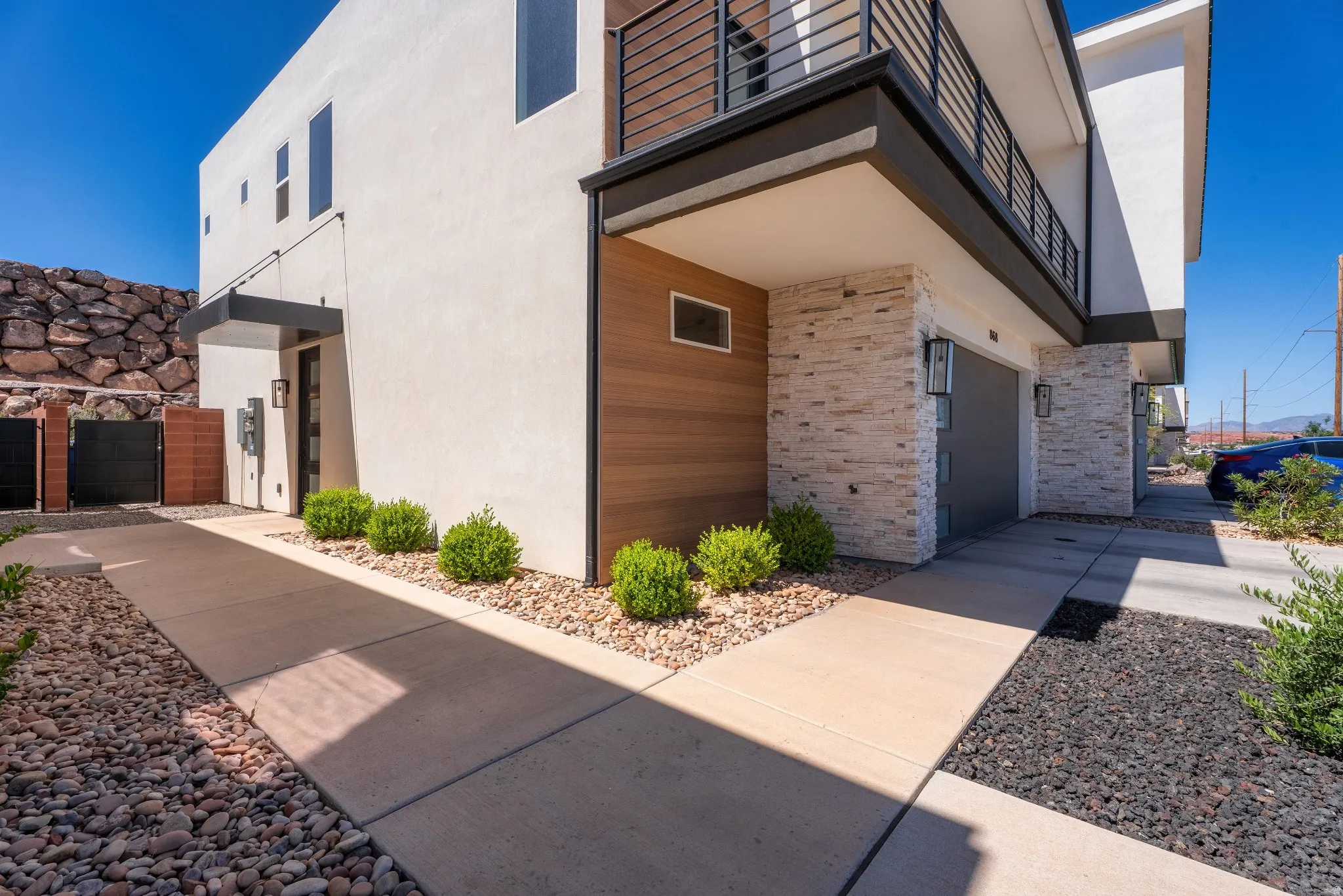 Contemporary exterior featuring stucco siding, wood-finish paneling, and stacked stone accents