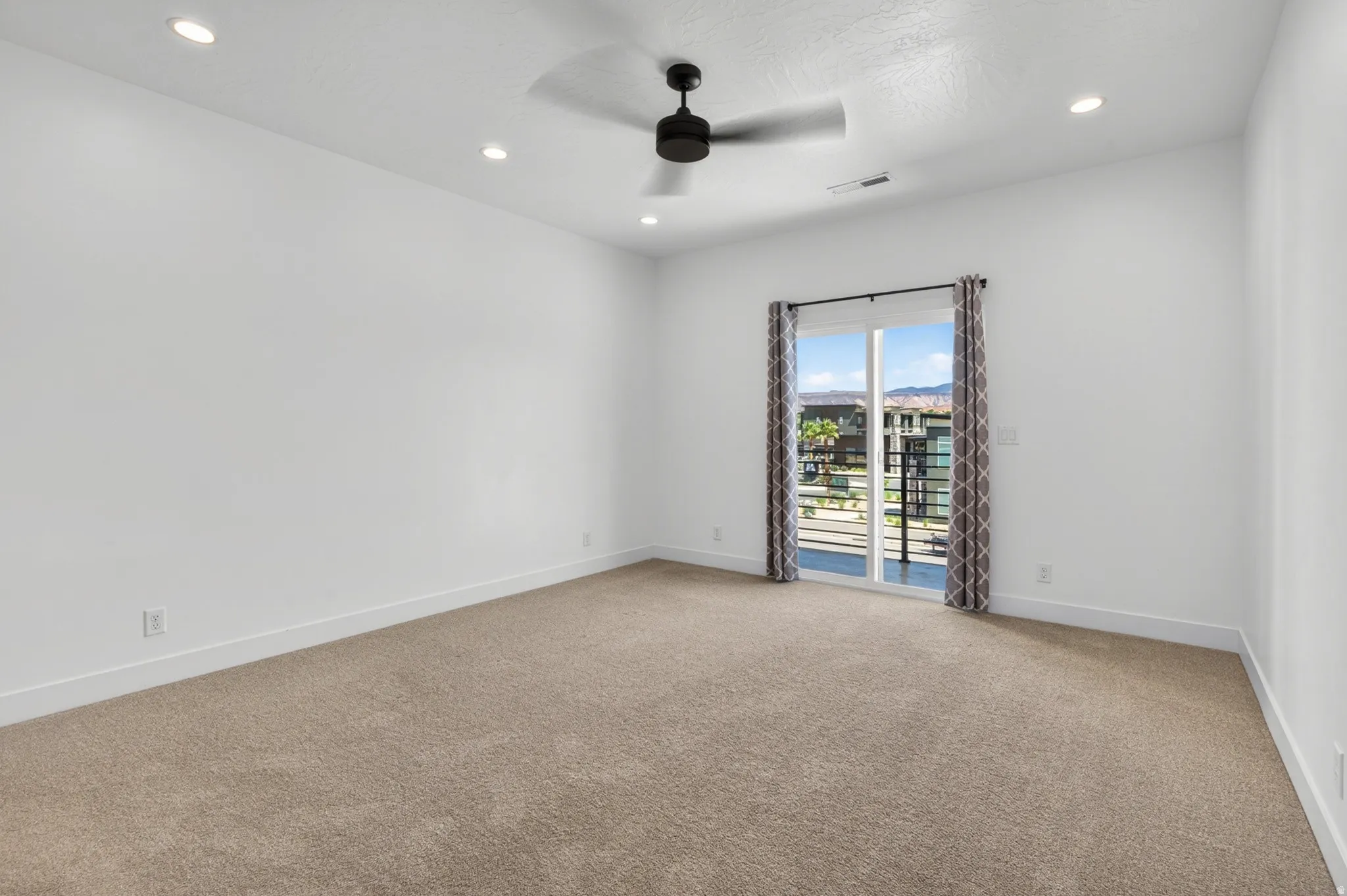 Spacious room featuring neutral carpeting, recessed lighting, and a modern ceiling fan