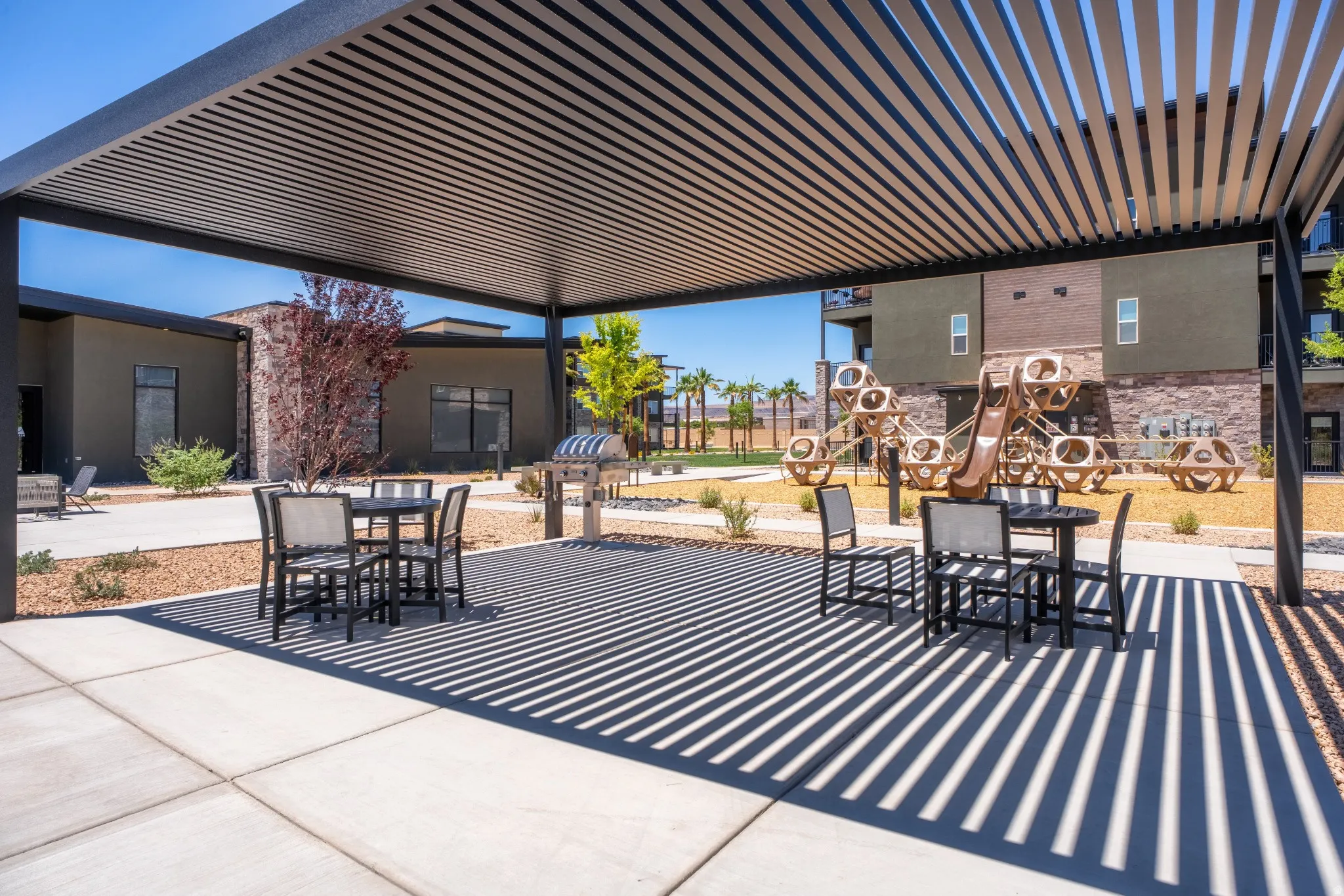 Patio area featuring a modern slatted pergola, concrete slab flooring, and a built-in barbecue grill