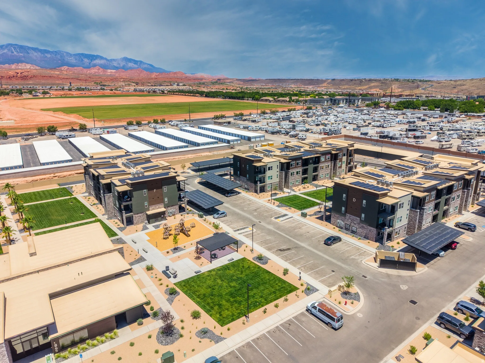 Modern multi-story buildings featuring stone and paneling exteriors, rooftop solar installations, and covered parking with integrated solar canopies