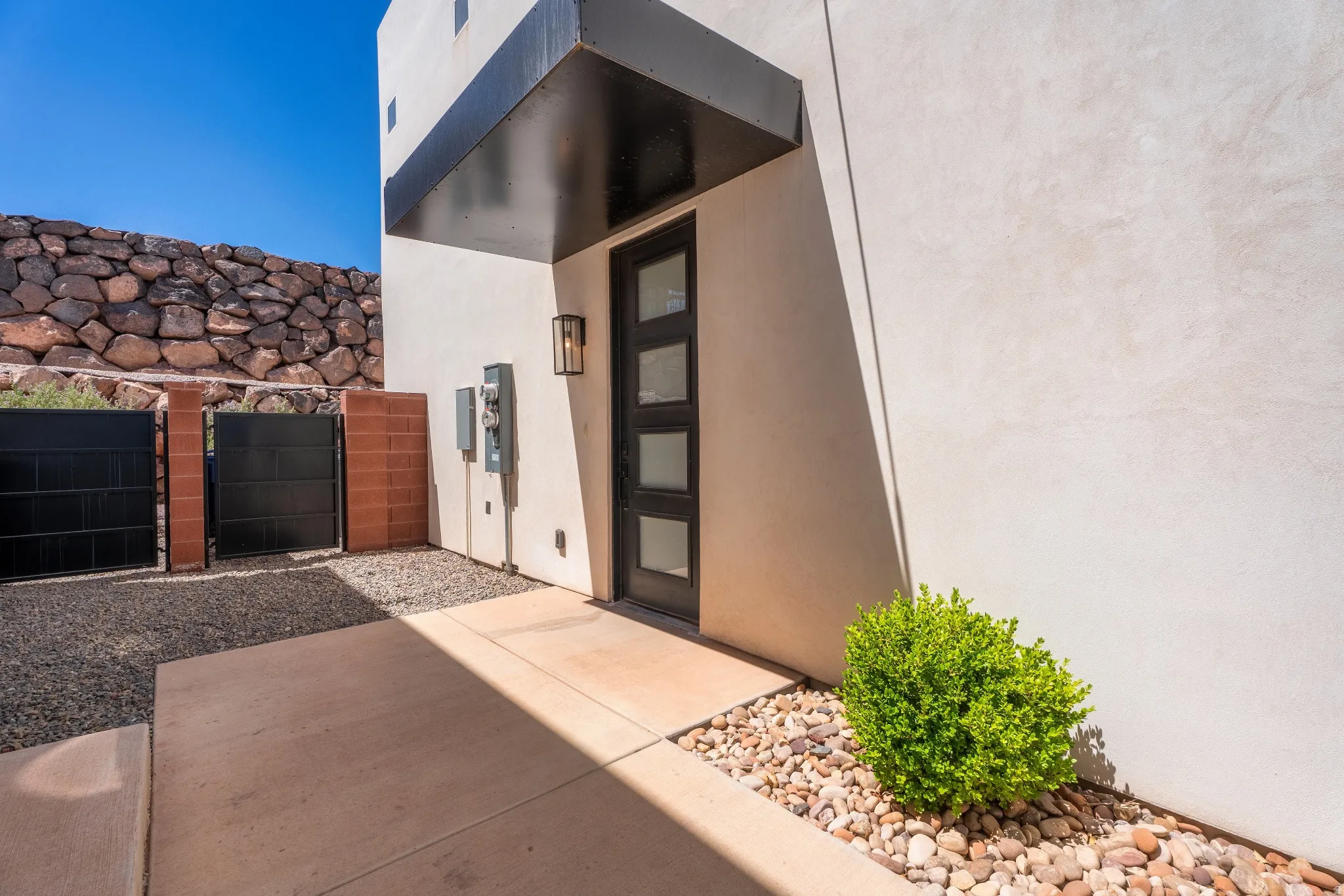 Modern entry featuring a dark-framed door with multiple glass panes, complemented by an overhead awning