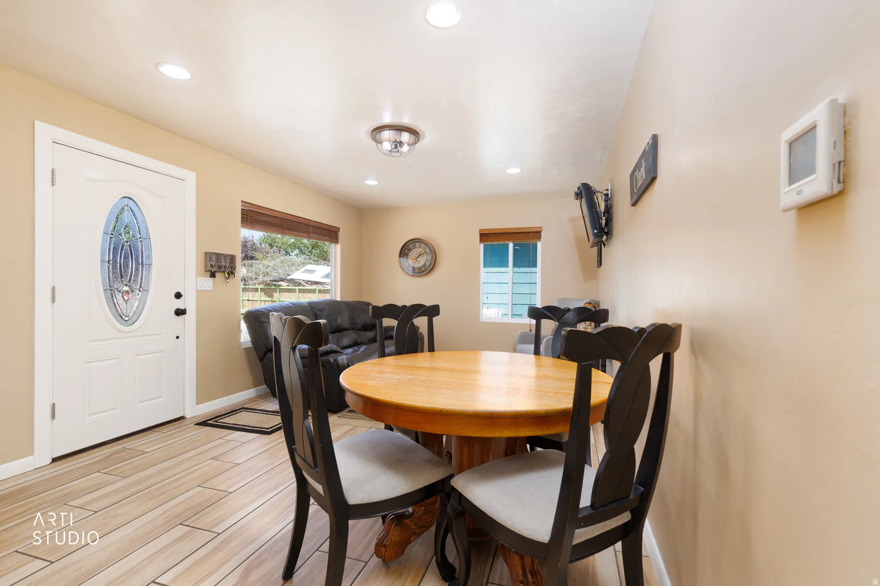 Entry area featuring a white door with an oval stained glass insert, wood-finish flooring, recessed lighting, and a window with blinds
