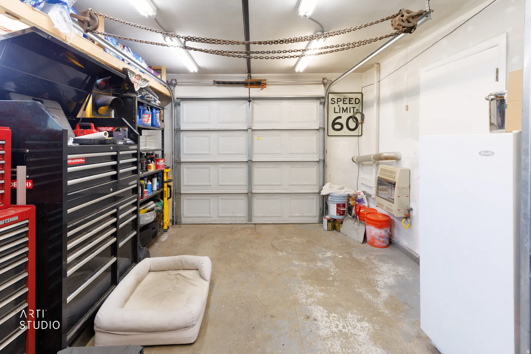 Interior garage space featuring a paneled garage door, exposed ceiling joists, and a concrete floor
