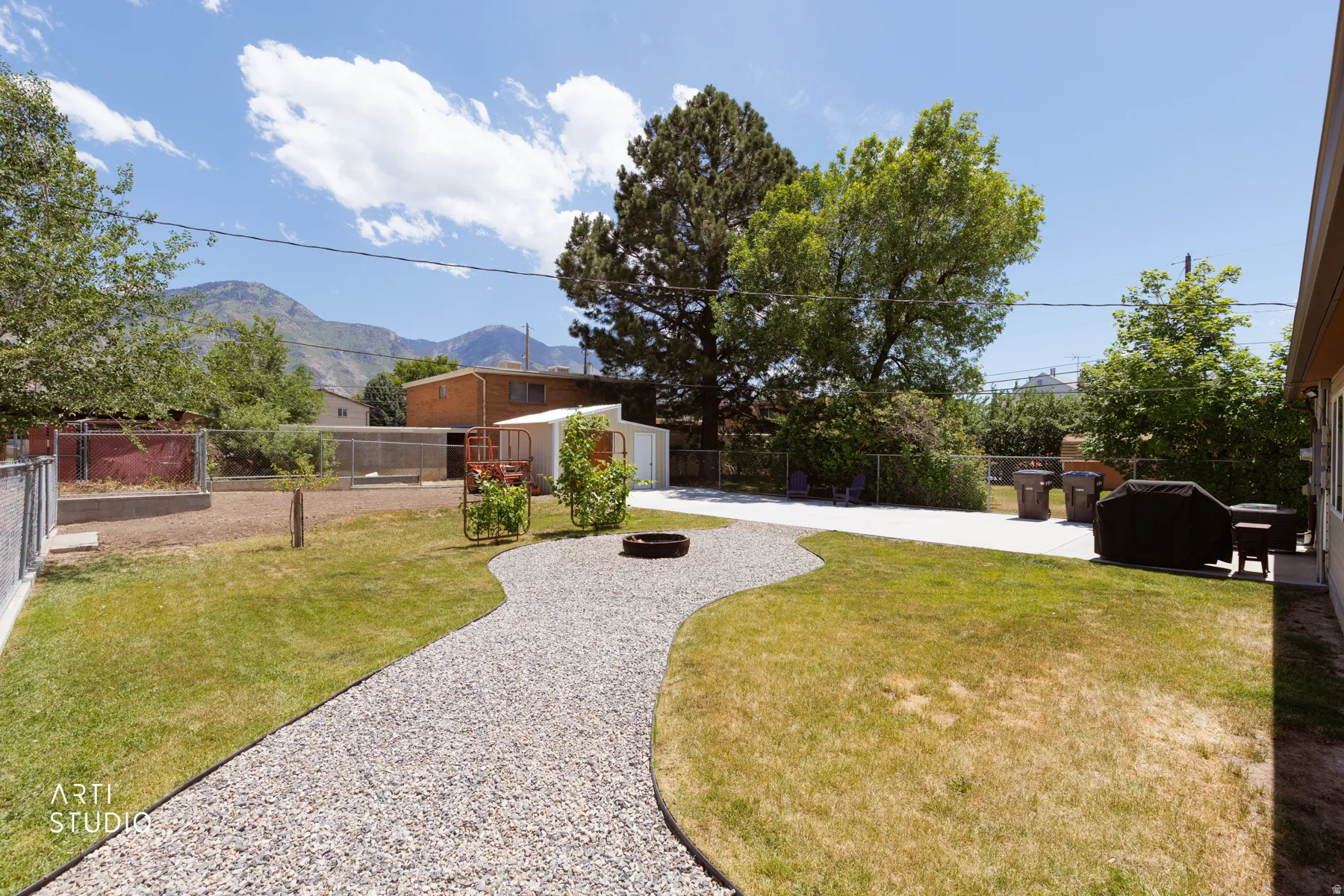 Expansive backyard featuring a winding gravel path, a concrete patio, and a manicured lawn