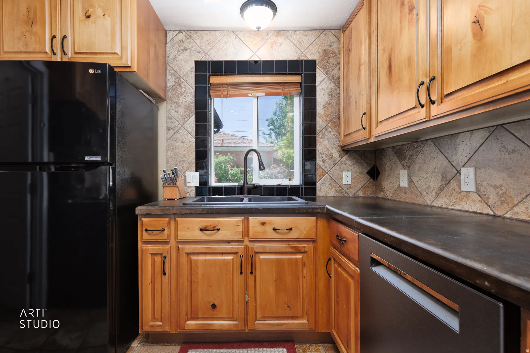 Kitchen featuring wood cabinetry, black appliances, a double basin sink with a high-arc faucet, and tiled backsplash