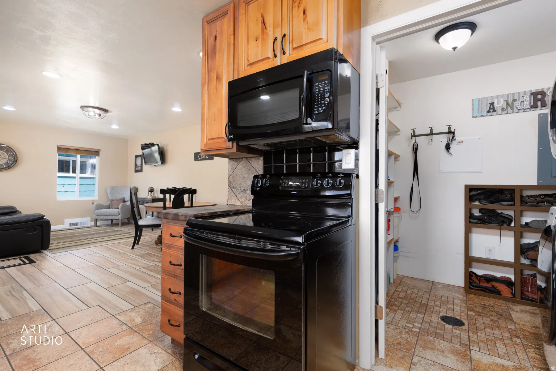 Kitchen area featuring black appliances, wood cabinetry, and a tile backsplash