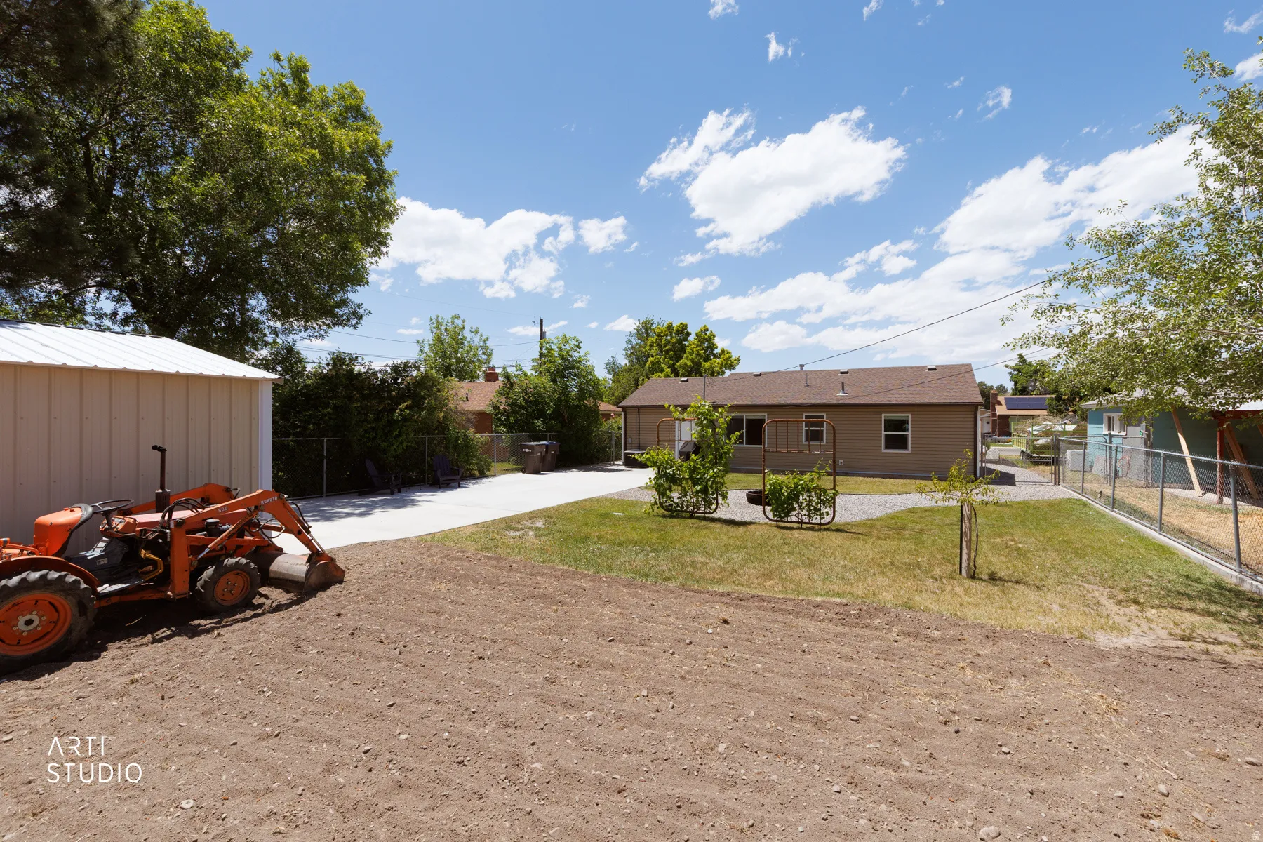 Expansive rear yard featuring a detached shed with a metal roof, a gravel driveway, and a partially fenced perimeter
