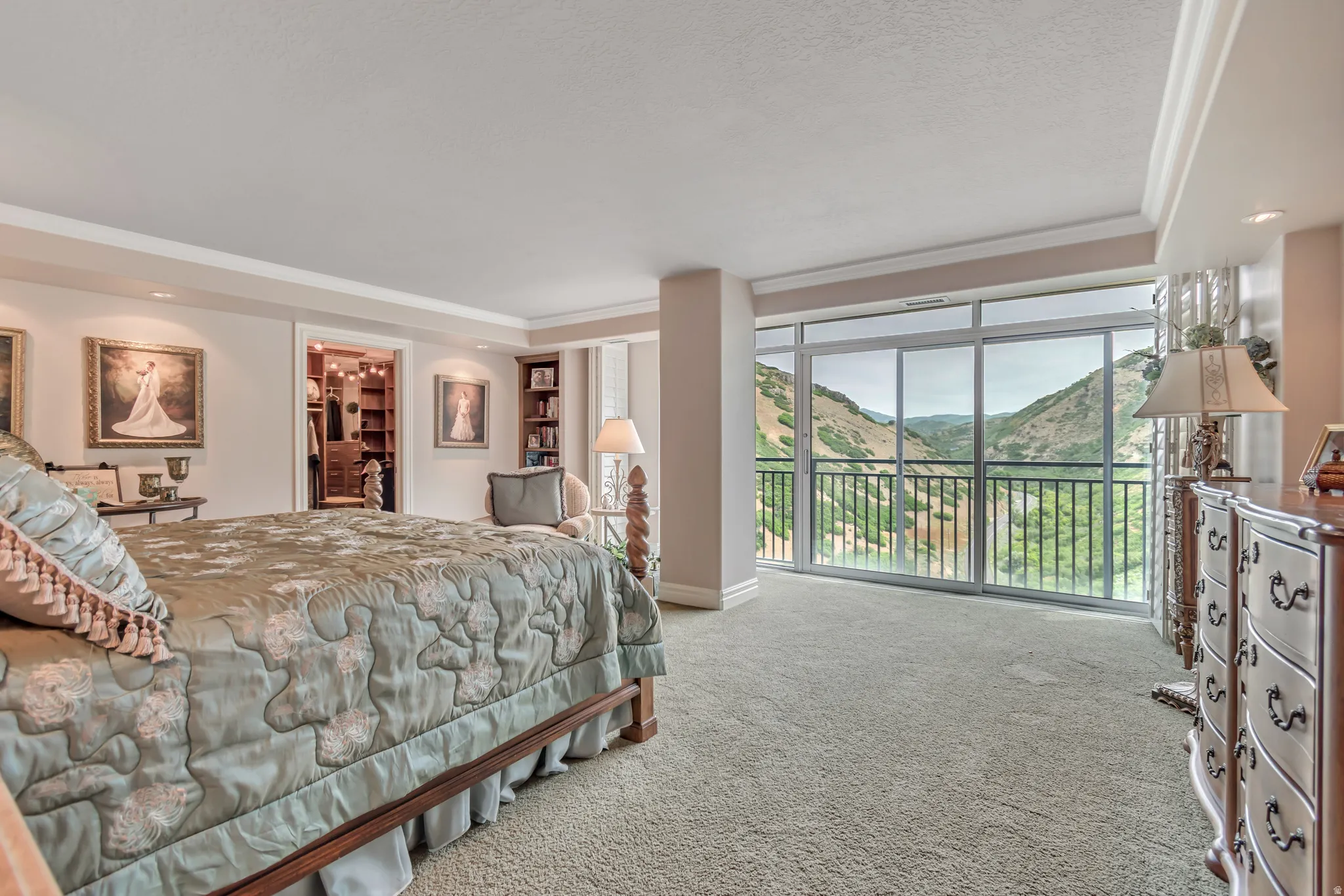 Master bedroom featuring a full-height glass sliding door, balcony with wrought iron railing, views of immigration canyon