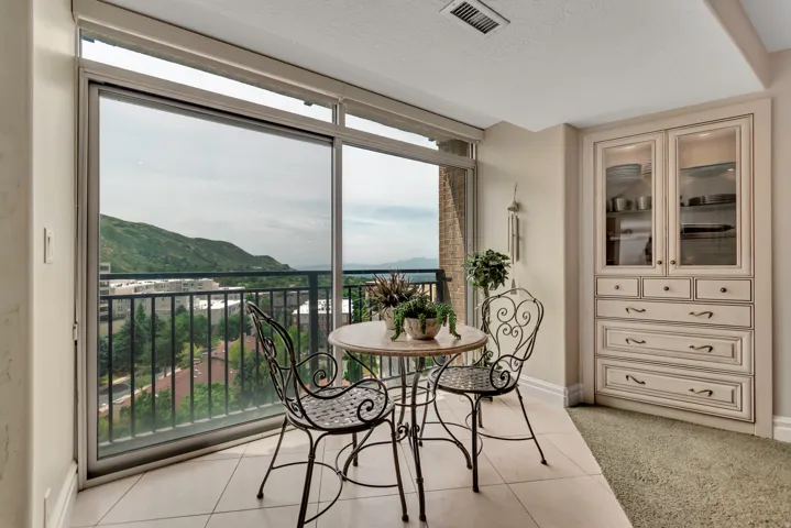 Sliding glass doors opening to a balcony with metal railing, featuring tile flooring and built-in cabinetry with glass display doors and lower drawers