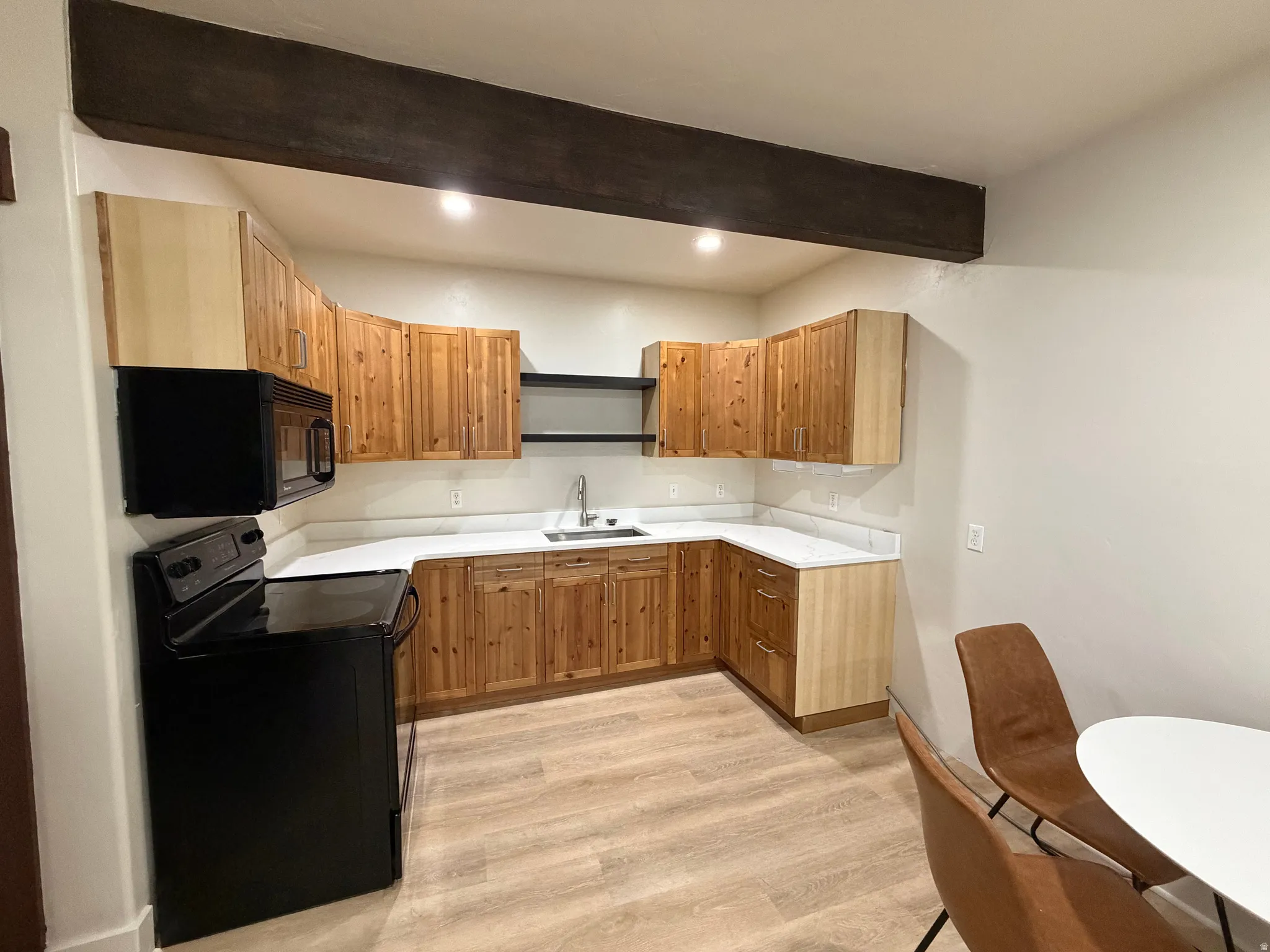 U-shaped kitchen featuring wood cabinetry, white countertops, and a black appliance suite