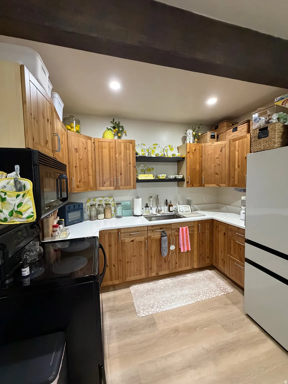 Kitchen featuring wood-finish cabinetry, light countertops, wood-finish flooring, and a stainless steel sink
