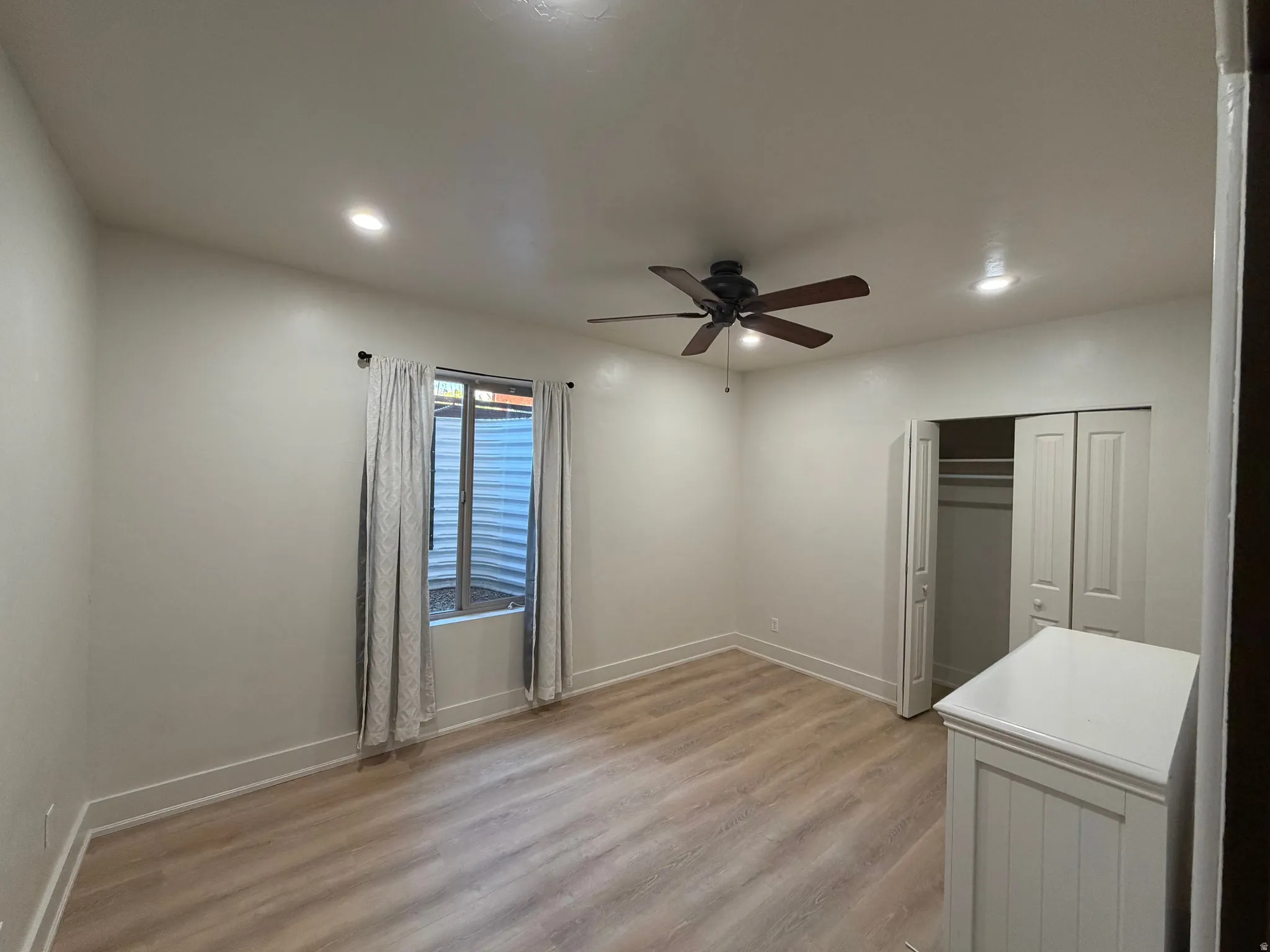 Neutral wall finishes with recessed lighting and a ceiling fan