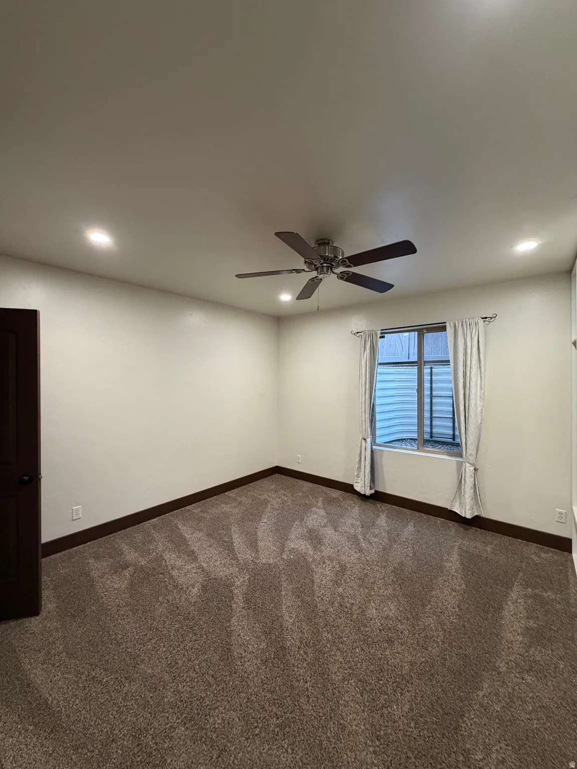 Spacious room featuring neutral wall finishes, plush carpeting, a ceiling fan with integrated lighting, and recessed ceiling lights