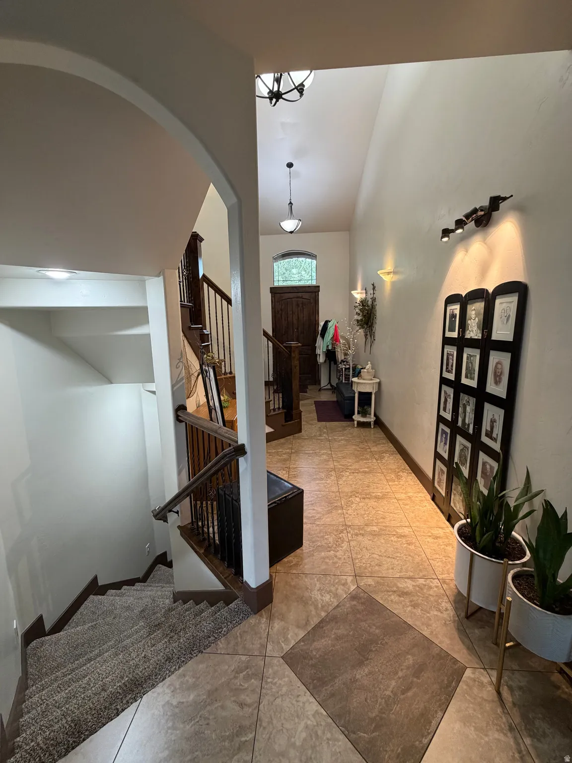 Entryway featuring a vaulted ceiling and an arched solid wood front door with a transom window