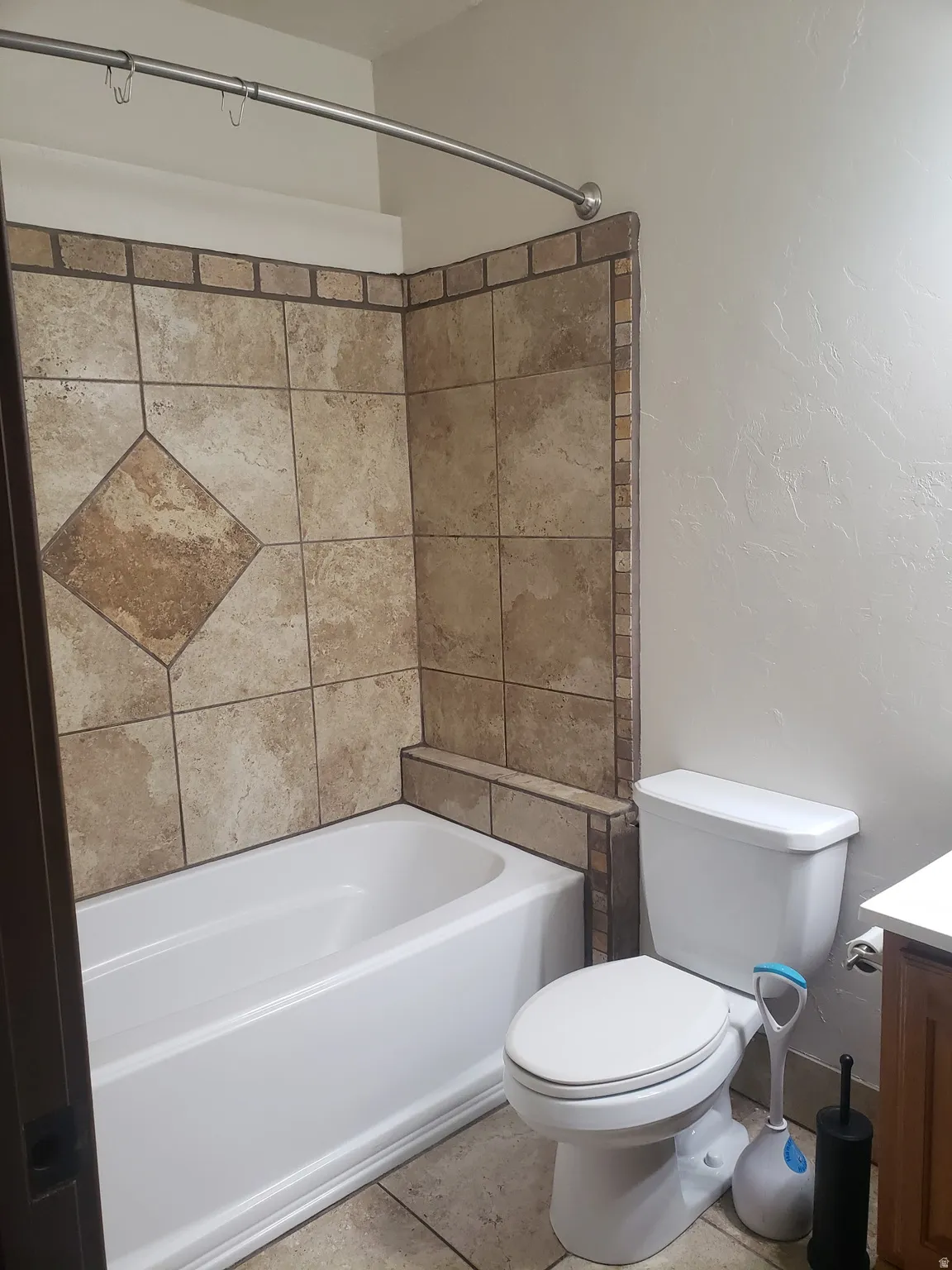 Full-size bathtub with surrounding tile wall featuring decorative accents