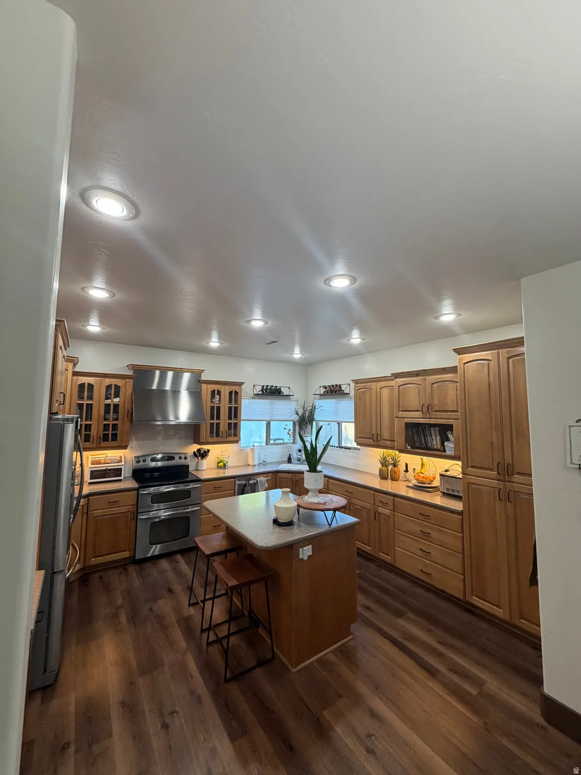 Spacious kitchen featuring warm wood cabinetry, a central island with seating, stainless steel appliances, and recessed lighting