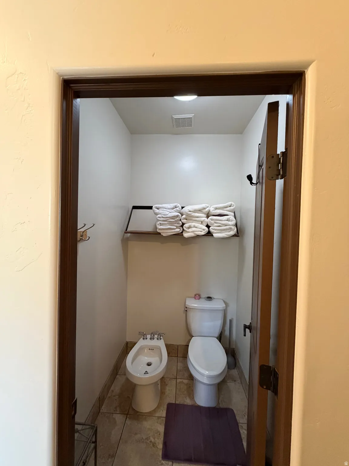 Private water closet featuring a toilet, bidet, tile flooring, built-in shelving, and recessed lighting