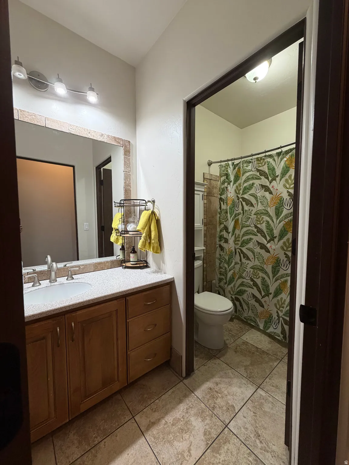 Bathroom vanity with wood-finish cabinetry, light-toned countertop, and integrated sink
