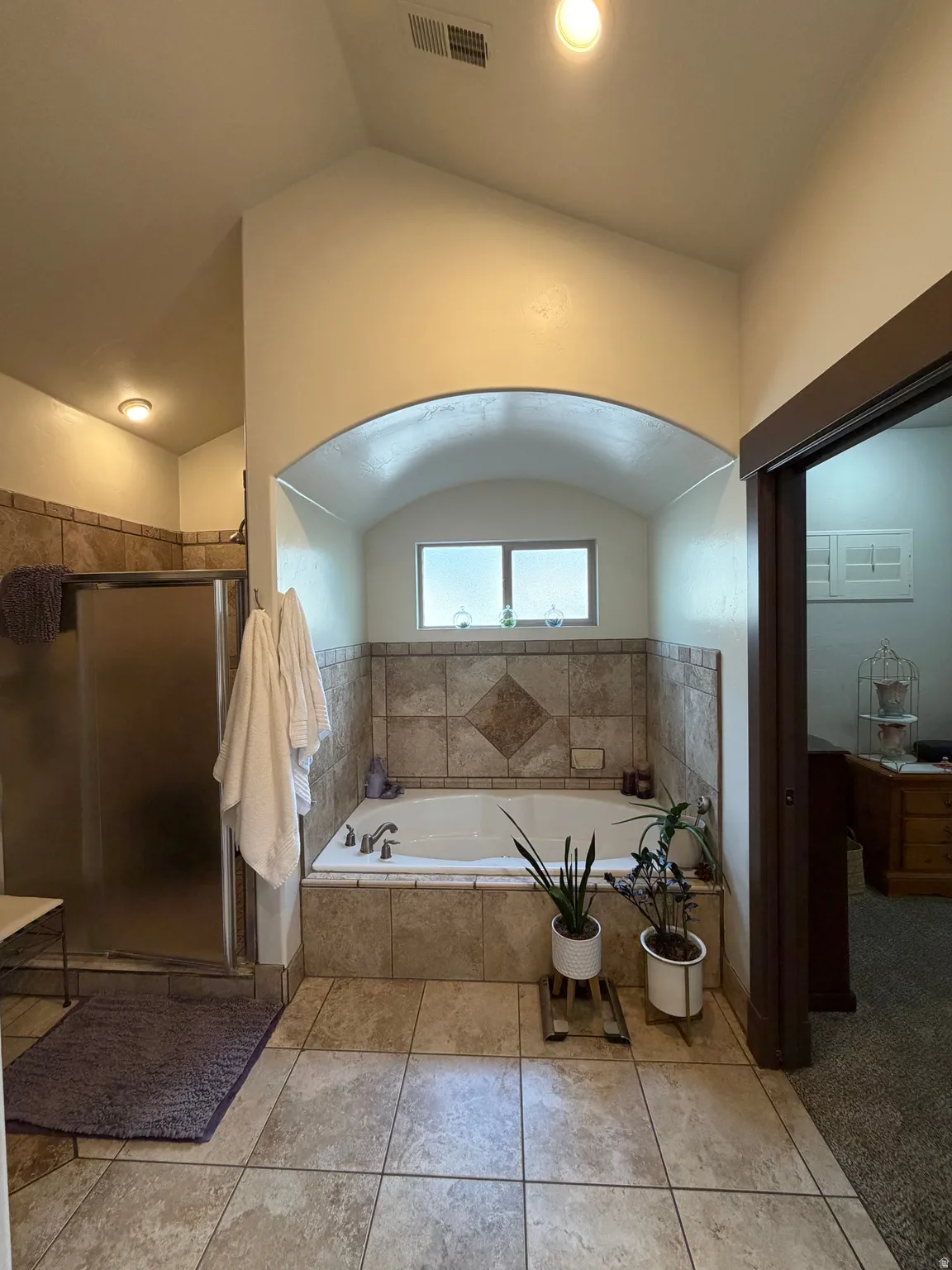 Bathroom featuring a built-in soaking tub with tile surround, a separate glass-enclosed shower, and tile flooring
