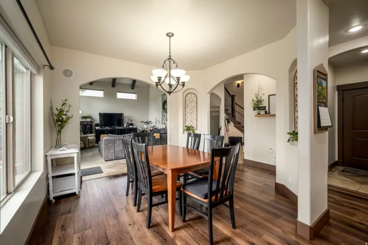 Wood-finish flooring throughout, arched doorways, a multi-light chandelier, recessed lighting, and large windows