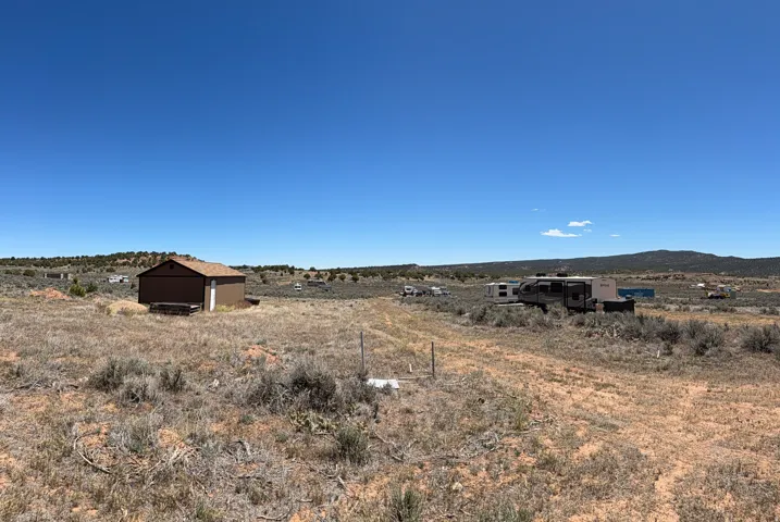 Expansive undeveloped land featuring a brown utility building with a white door and shingle roof