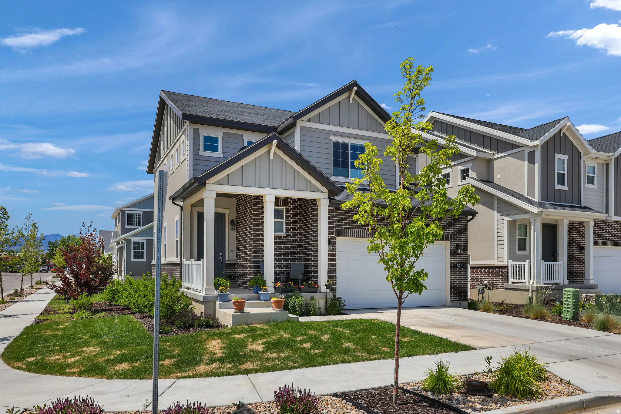 Contemporary multi-story residence featuring a covered front porch, a two-car garage, and a brick and siding exterior